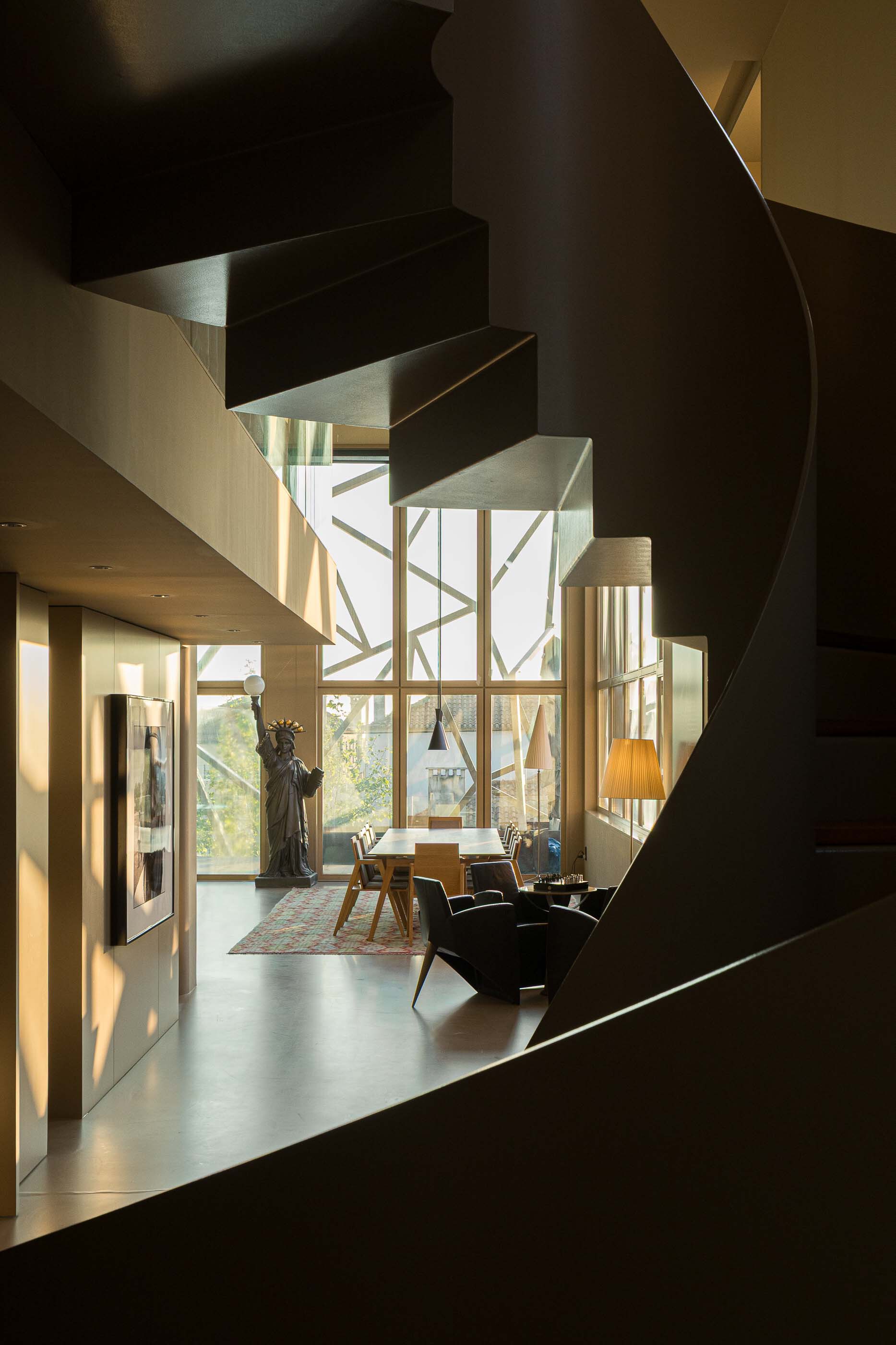 Sculptural helical staircase wrapping around a central void overlooking the glazed living area below