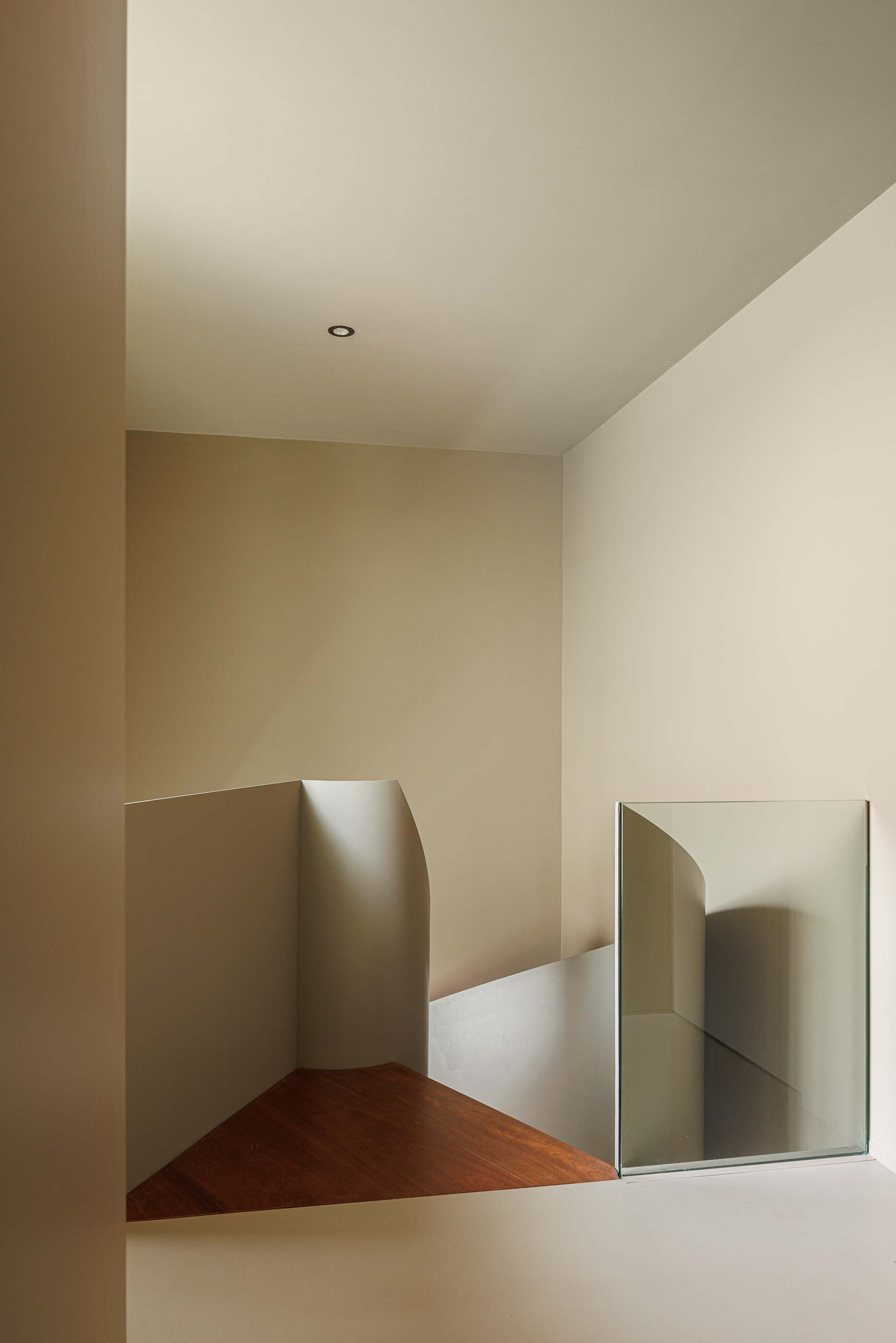 Upper-level corridor with angled walls, timber flooring, and rectangular mirror reflecting adjacent passageway