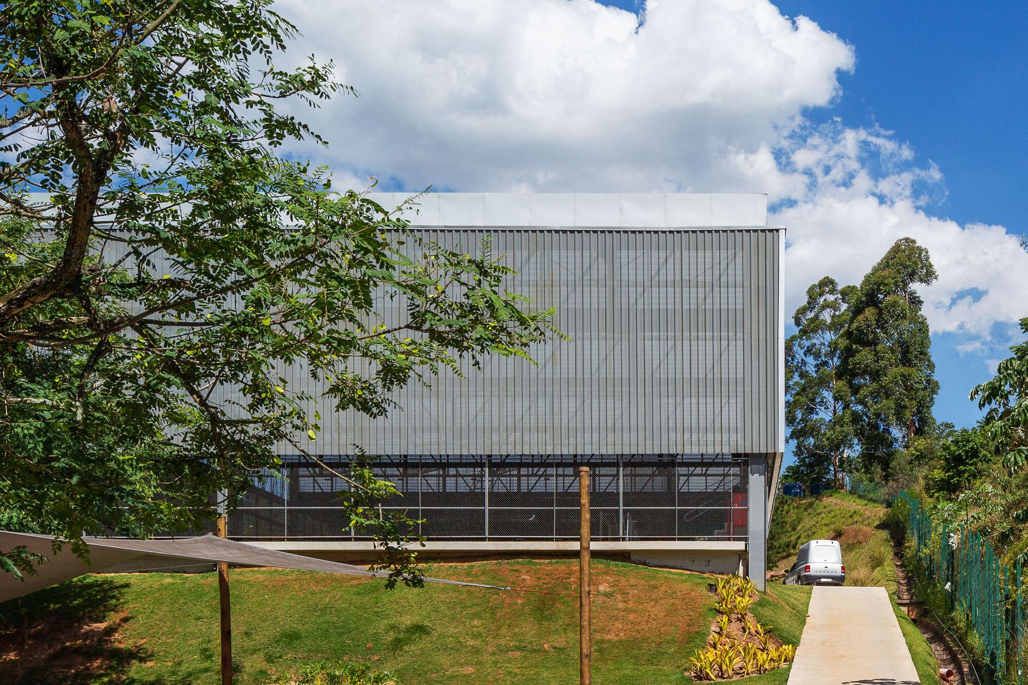 Two-story facade with vertical metal cladding and horizontal glazed strip on a sloped site