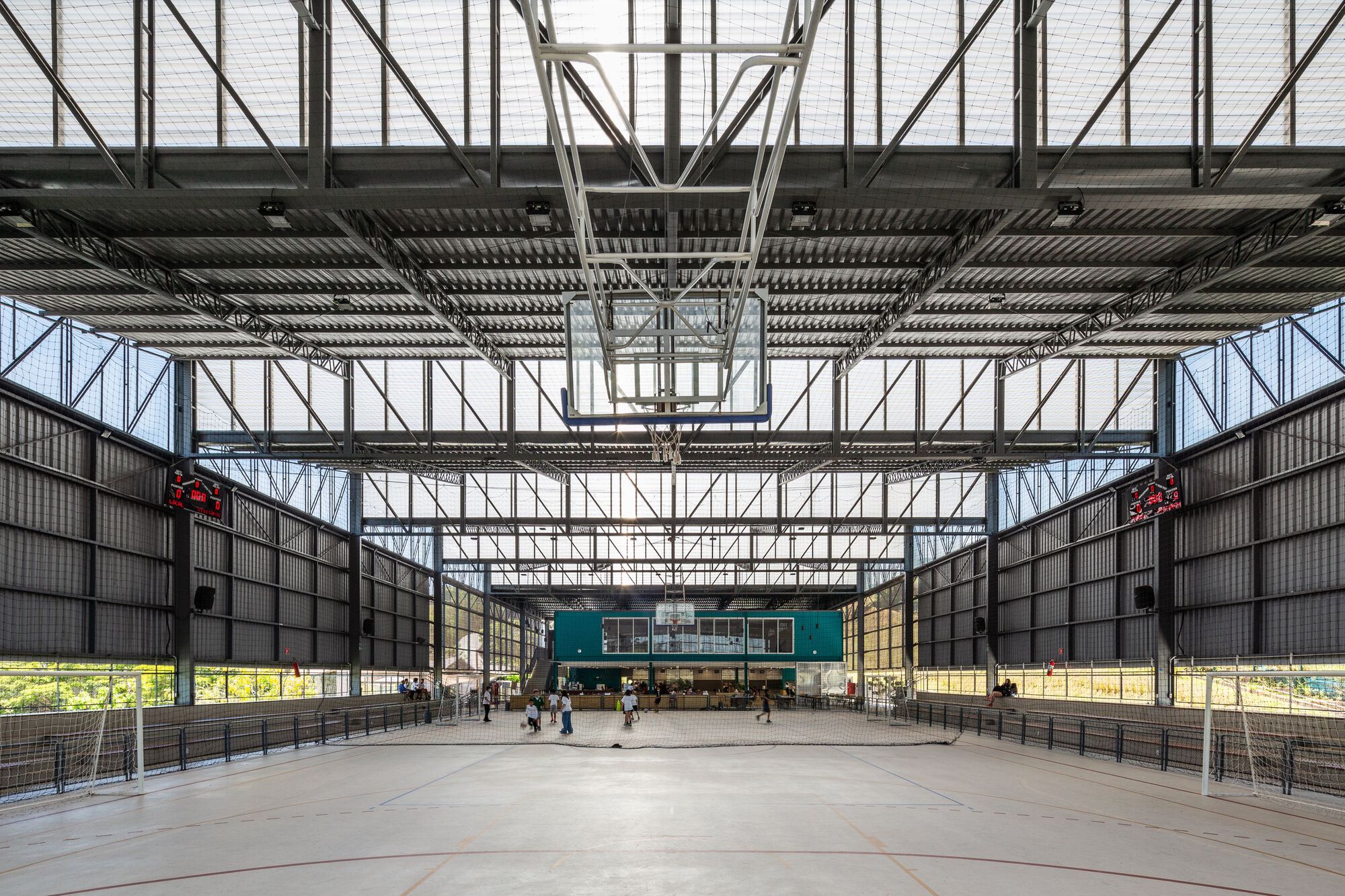 Full-height steel truss structure framing a large covered court with concrete floor