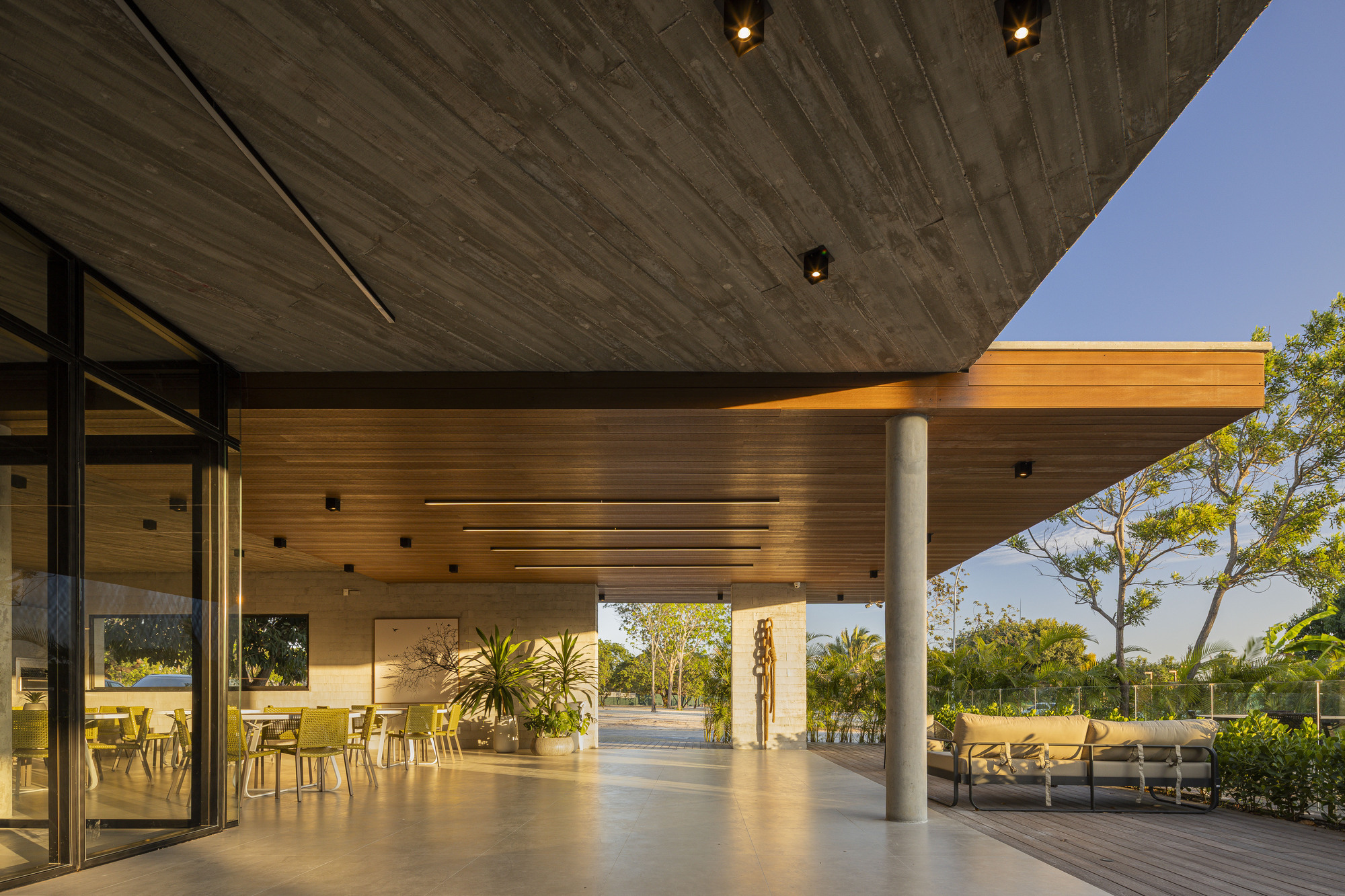 Covered terrace at dusk with board-formed concrete and timber ceilings supported by concrete columns