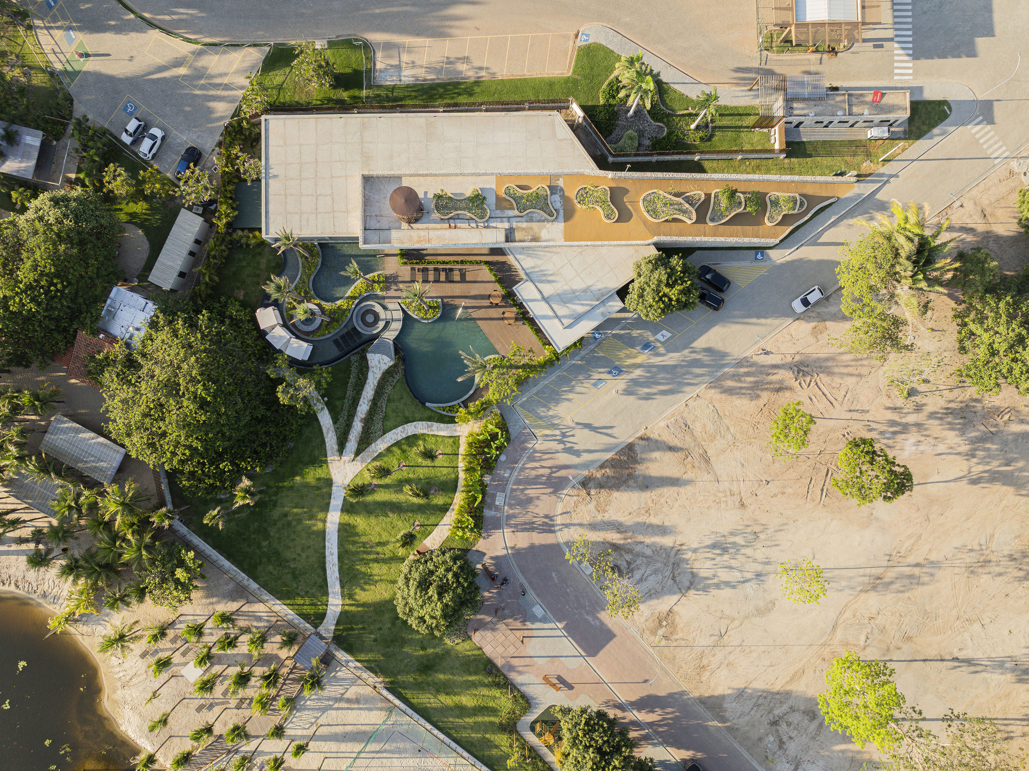 Aerial view of curving terraced plaza with organic planting beds and paved pathways connecting landscape features