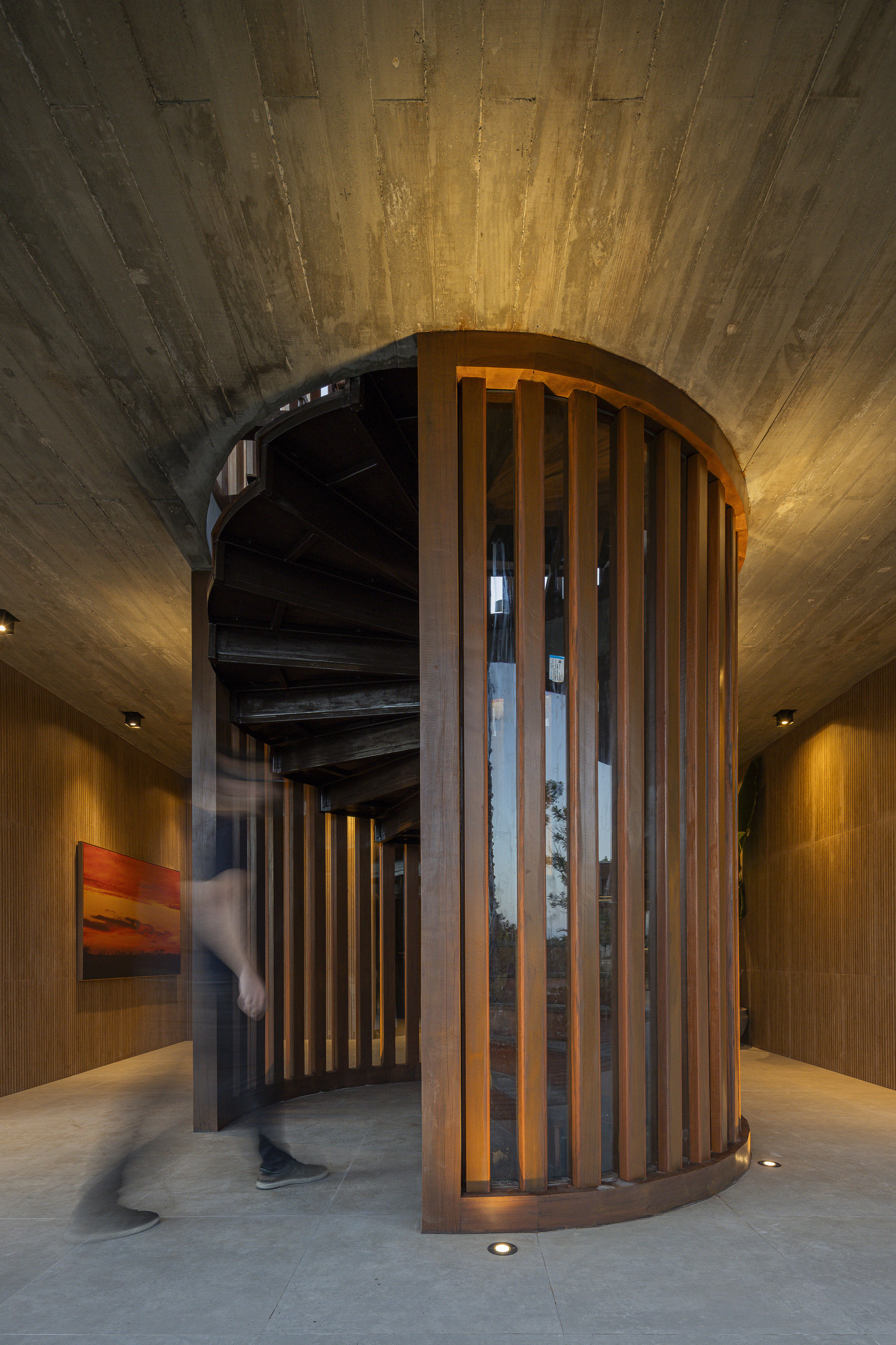 Close-up of the cylindrical timber screen with vertical slats and spiral staircase visible inside
