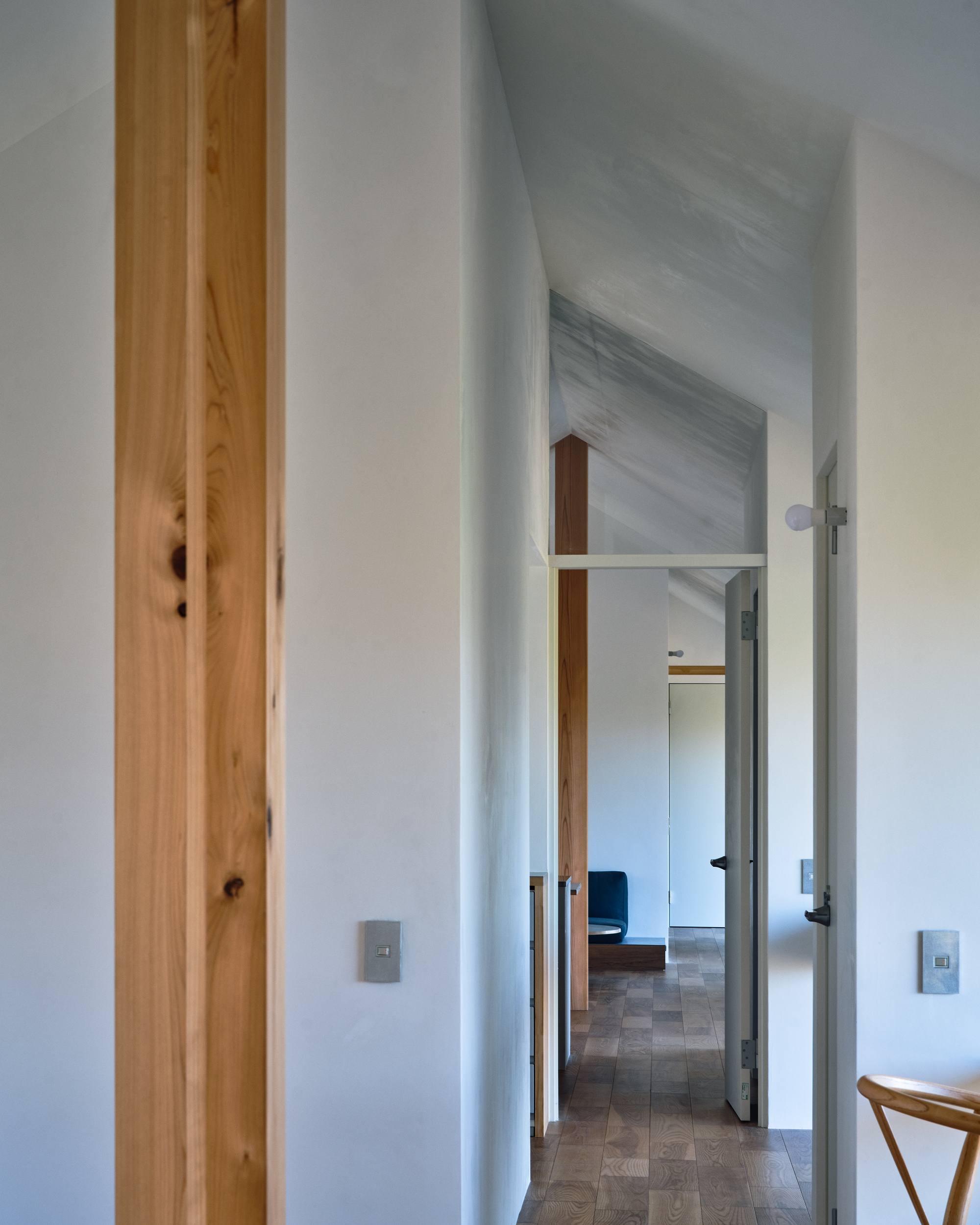 Hallway with exposed timber post beside doorways leading through white-walled rooms with vaulted ceilings