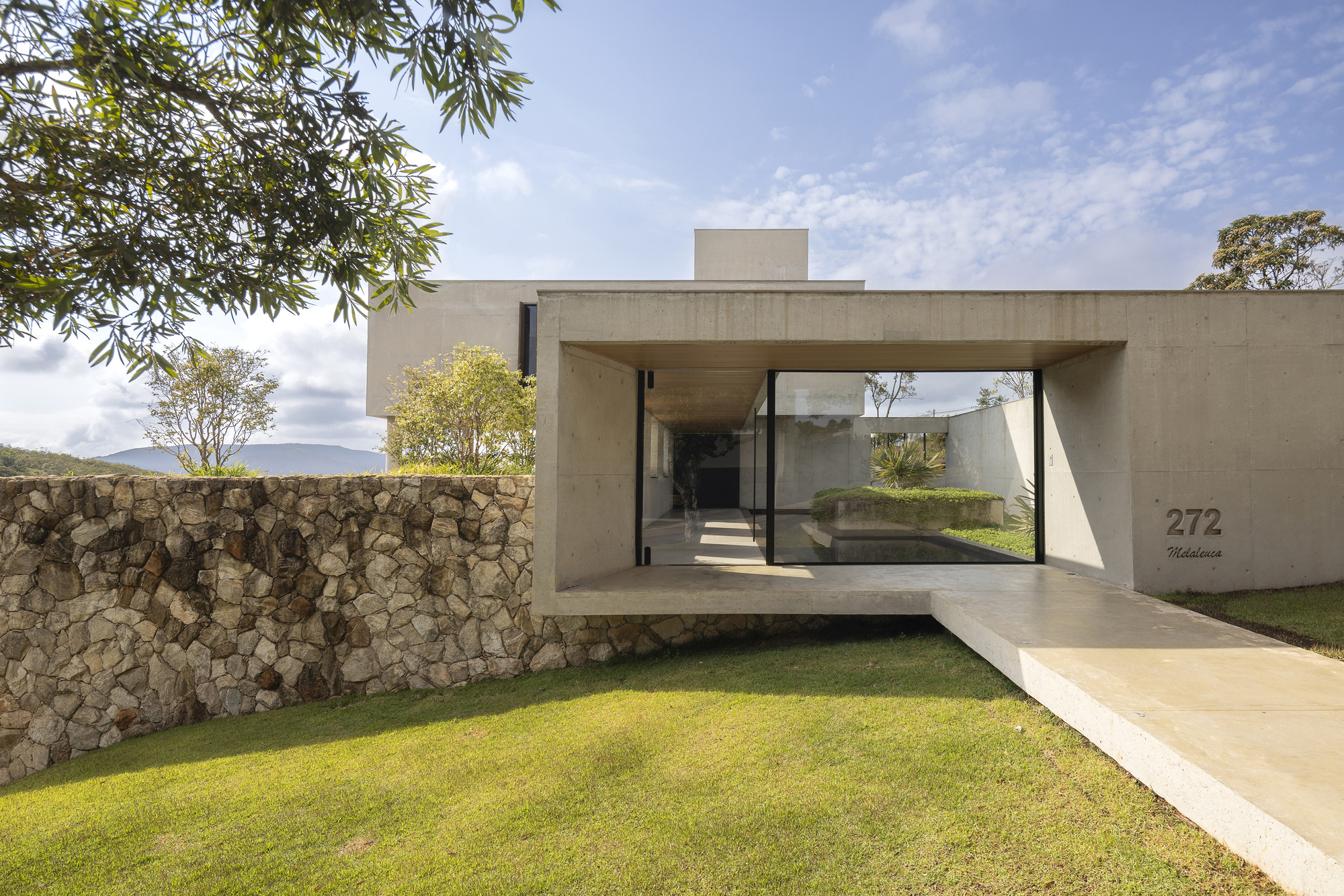 Cantilevered concrete entry bridge framing a view through to the interior courtyard beyond