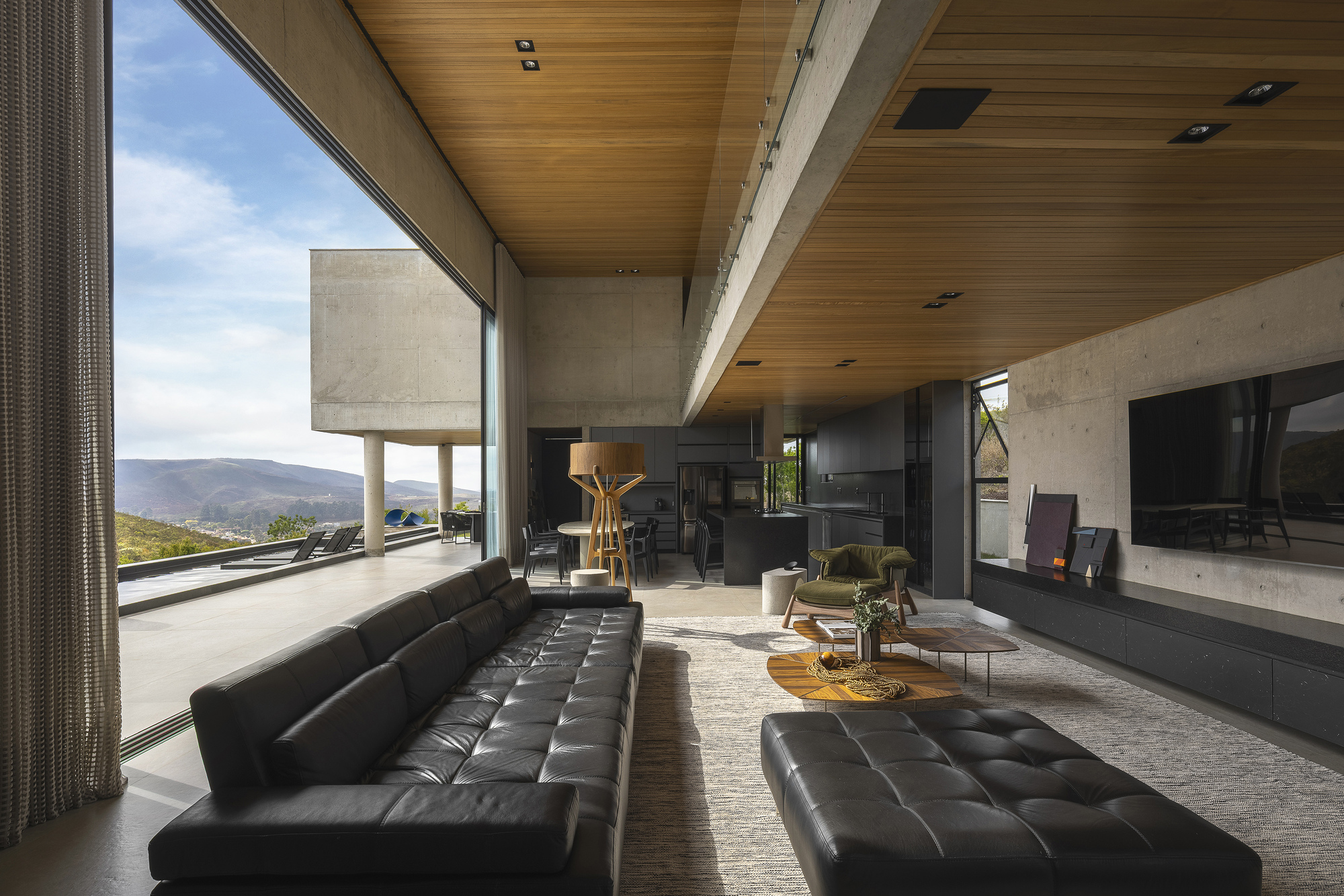 Living room with timber ceiling and floor-to-ceiling glass overlooking distant mountain landscape