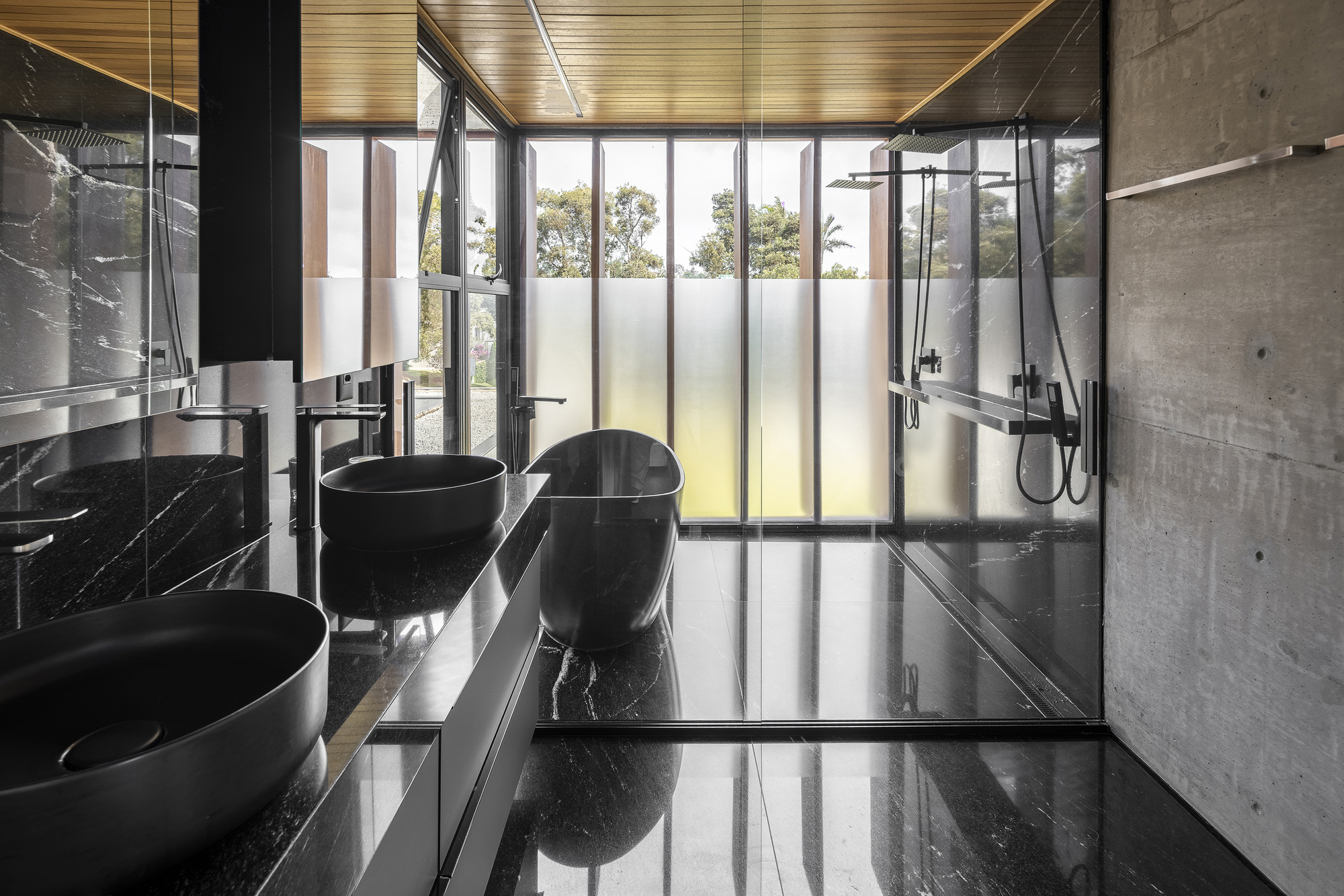 Bathroom with black marble surfaces, concrete walls, and translucent glazing panels with daylight