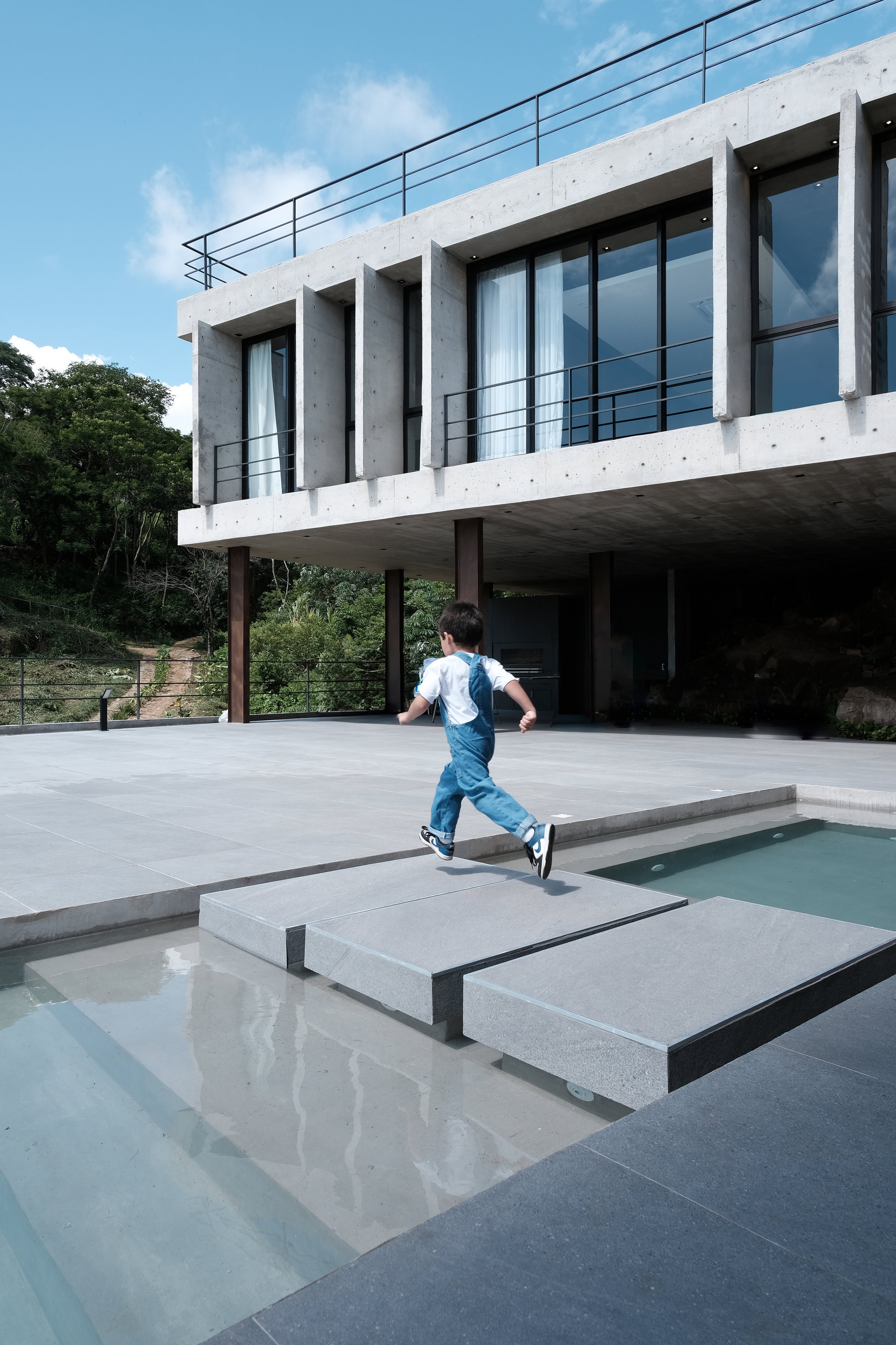 Child running across a pool deck with concrete stepping pads beneath the elevated concrete structure