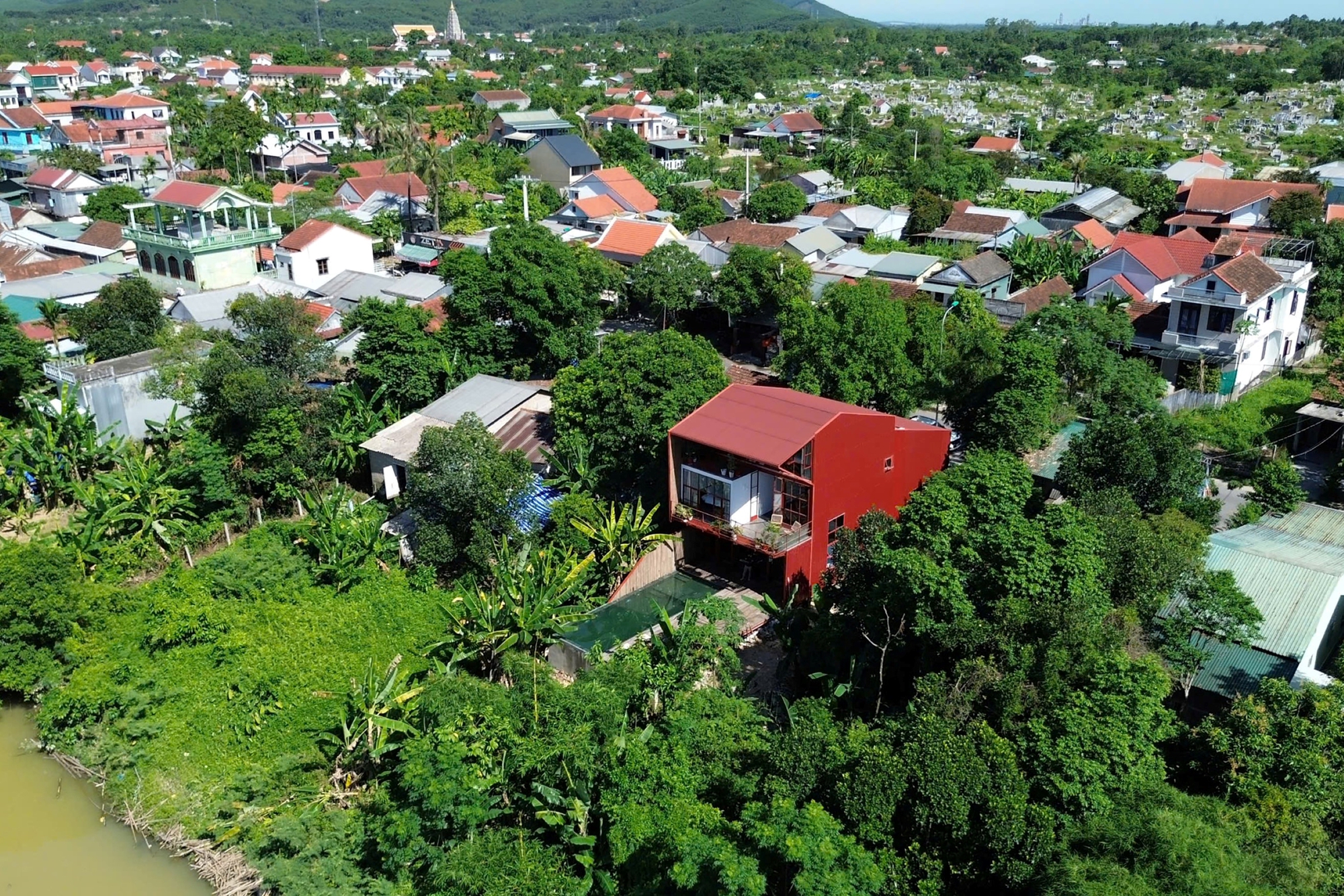 Aerial view of the red steel house nested among trees in a dense residential neighborhood