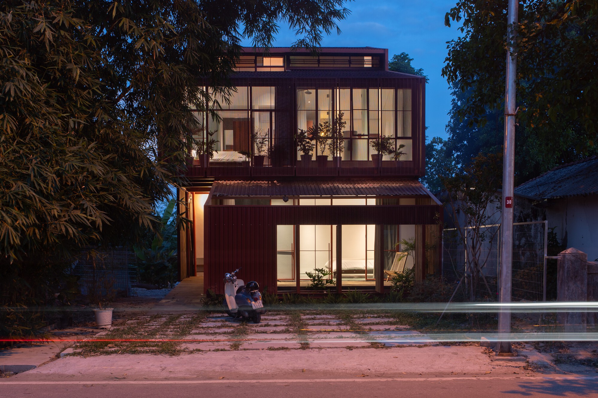 Two-story facade with full-height glazing and corrugated metal cladding illuminated at dusk