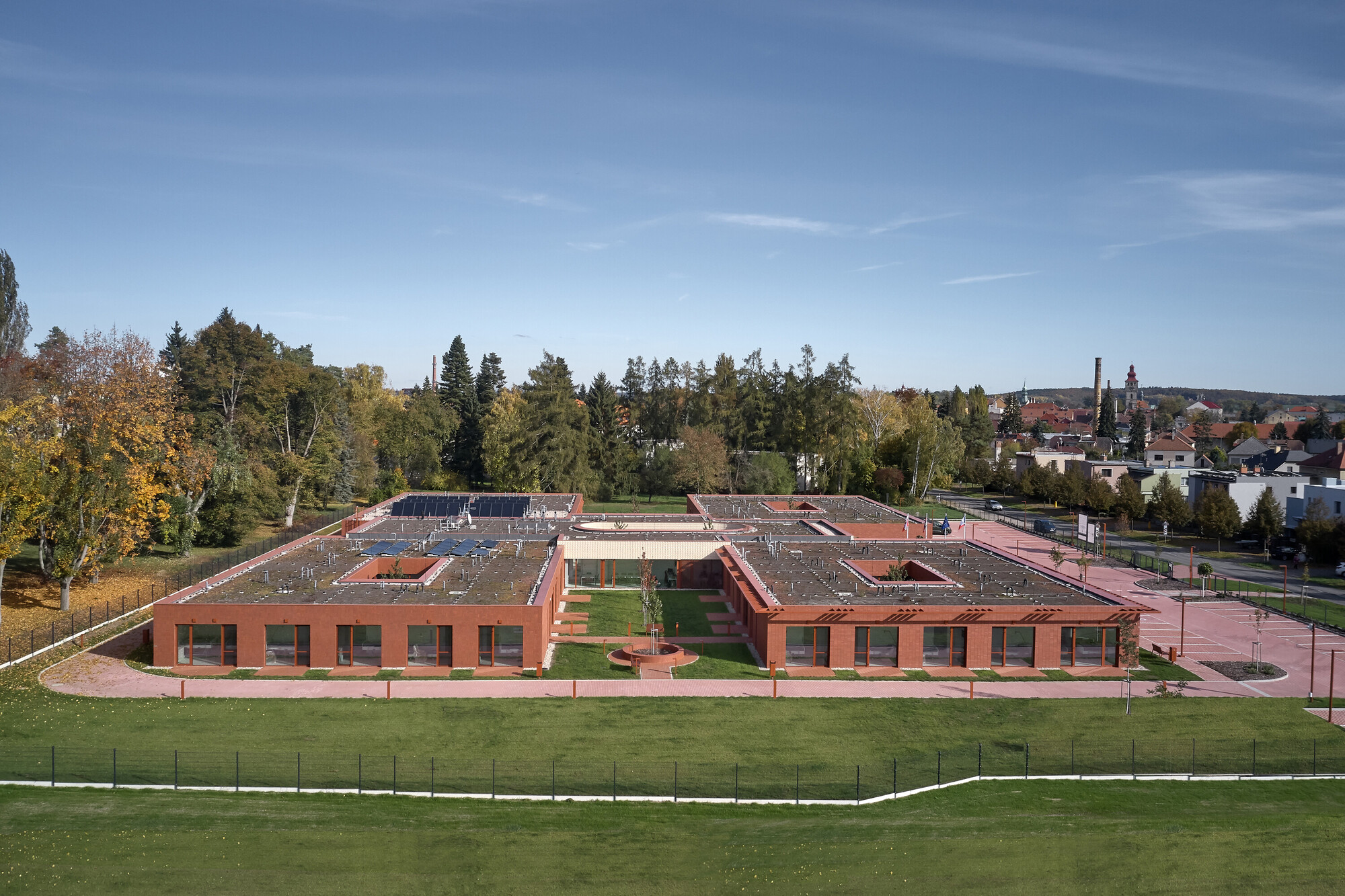 Aerial view of the red brick quadrangle with green rooftop courtyards and surrounding sports fields