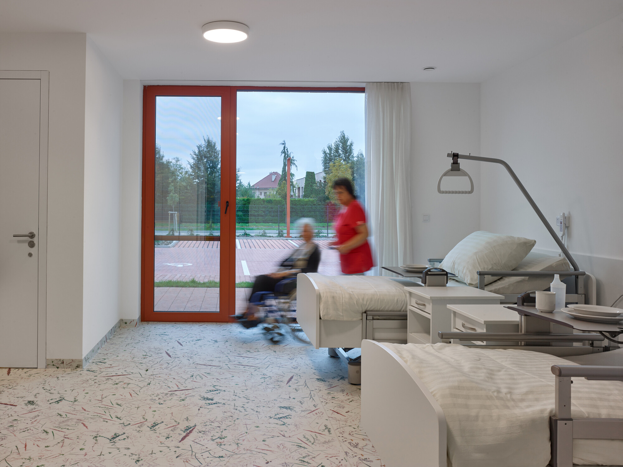 Interior corridor with terrazzo flooring and blurred figures passing through doorway in motion