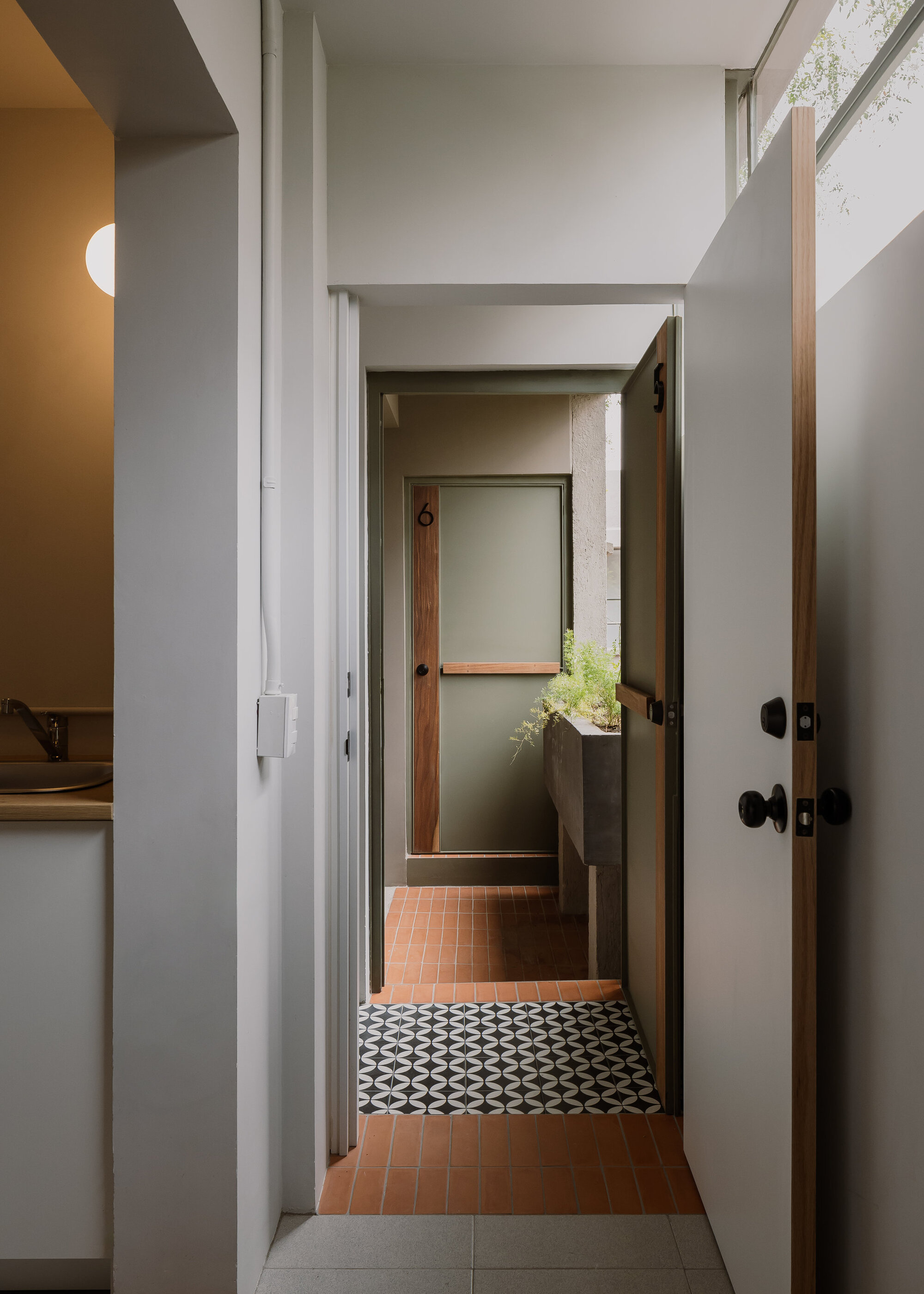 Hallway view through multiple doorways revealing terracotta tile floor and geometric patterned threshold