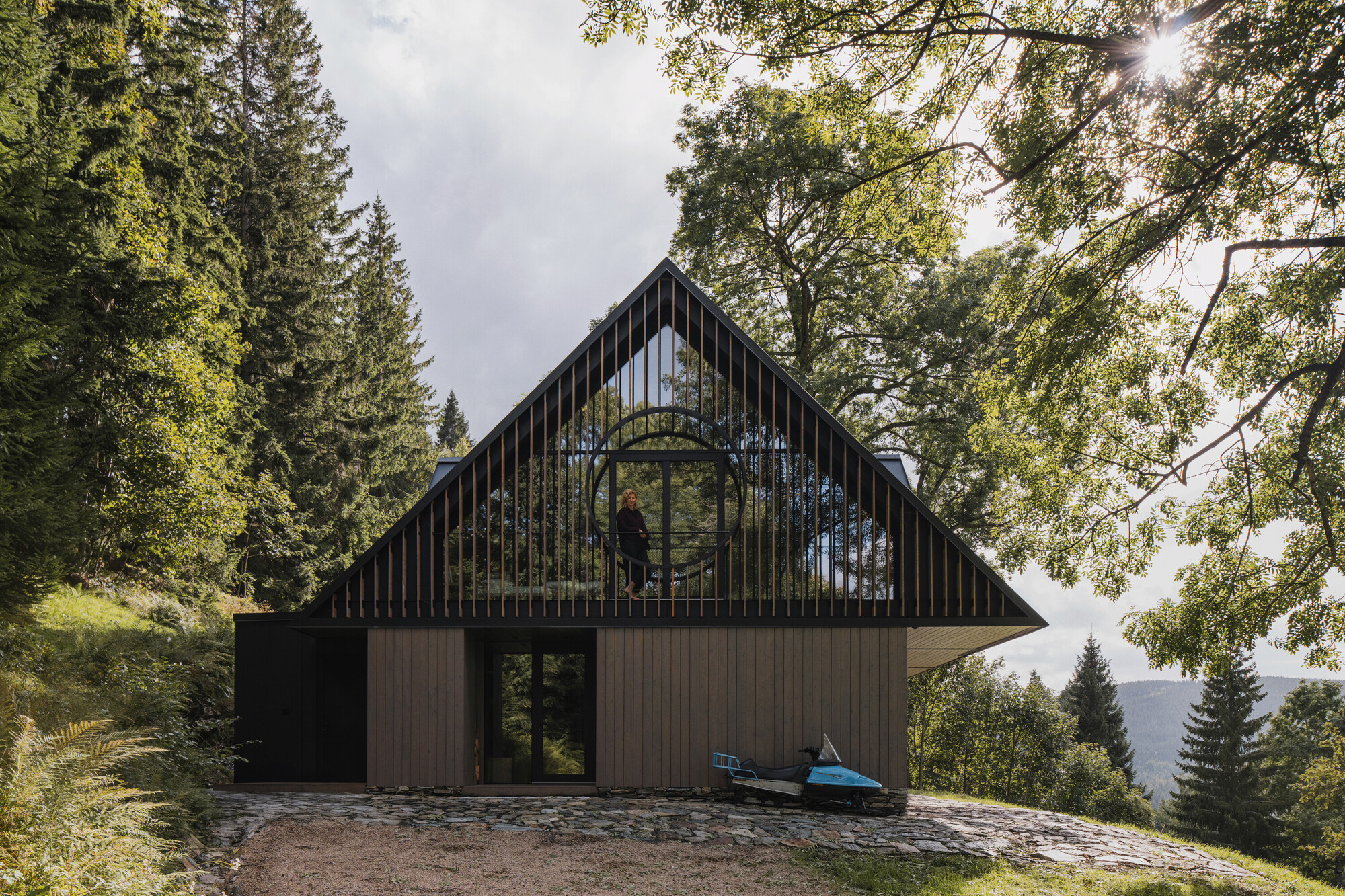 Rear elevation with vertical slat gable and a figure standing in the circular window opening