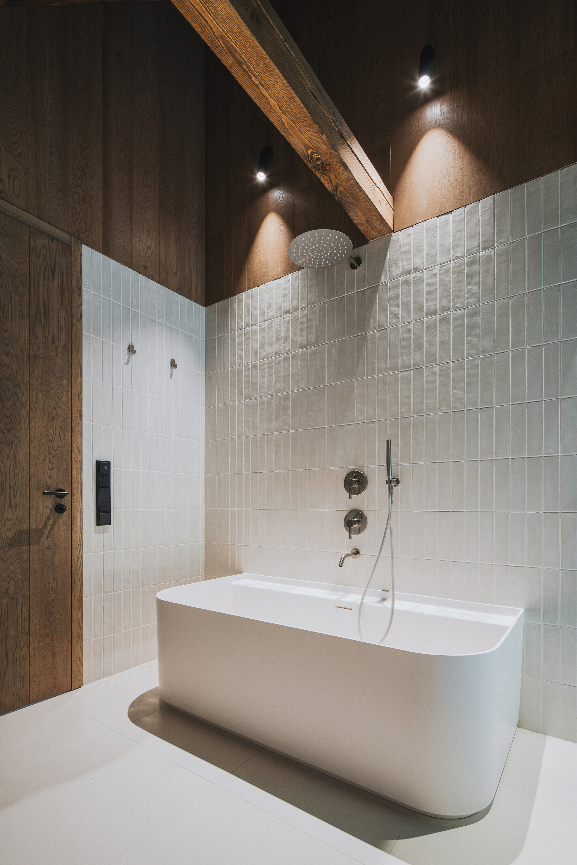 Freestanding bathtub below white subway tile walls and a timber ceiling with recessed lighting