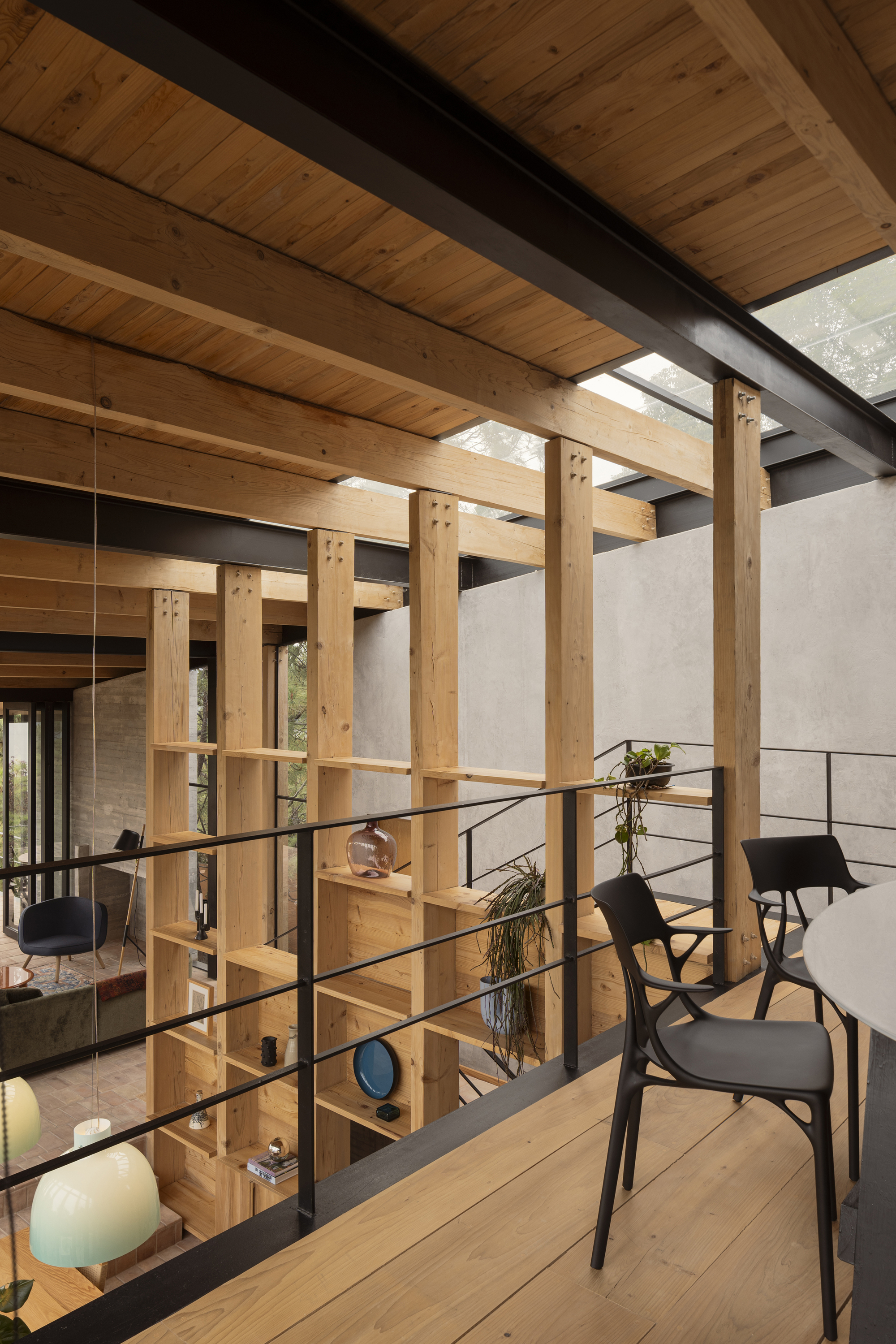 Timber shelving screen with metal railing dividing upper level beneath wood plank ceiling and black steel beams