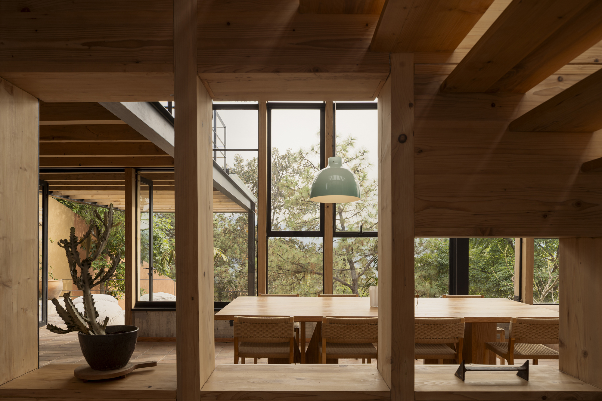 Dining nook with built-in timber benches under tall windows framed by exposed wood columns and beams