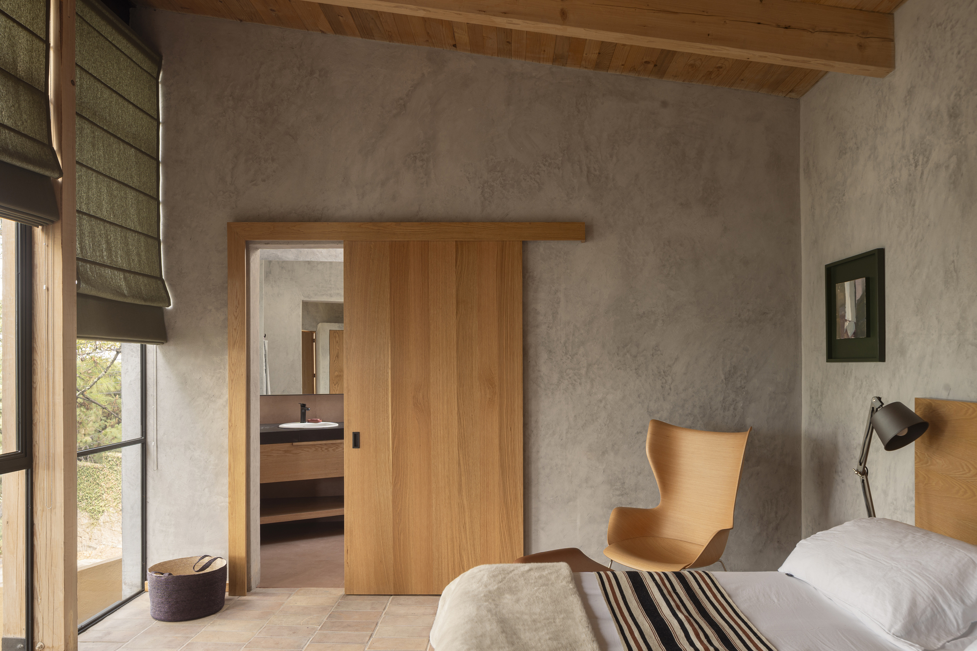 Bedroom with sliding timber doors opening to an ensuite beneath an exposed wood beam ceiling