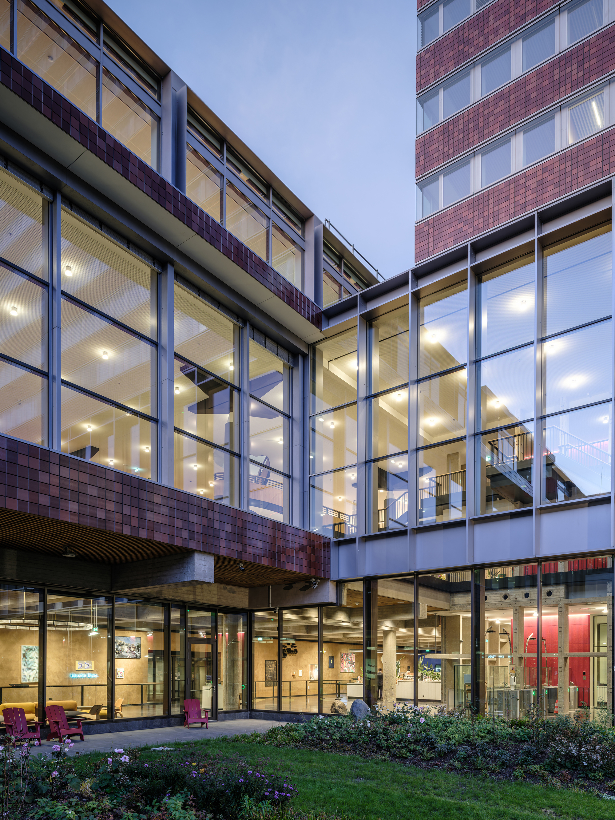 Corner view of the glass curtain wall above a covered entry at dusk
