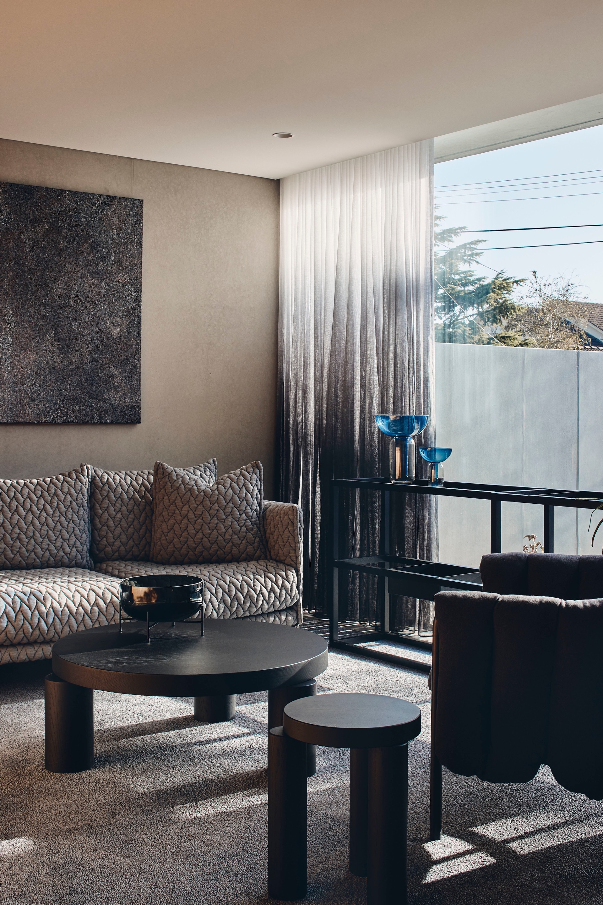 Living room with gradient curtains and floor-to-ceiling window overlooking trees and concrete wall