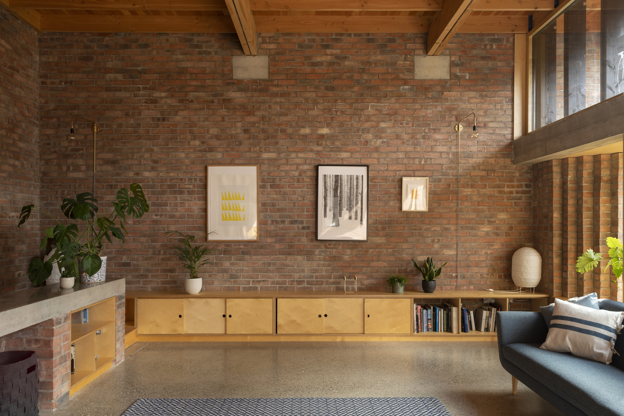 Plywood storage wall with open shelving beneath exposed rafters and mezzanine level above