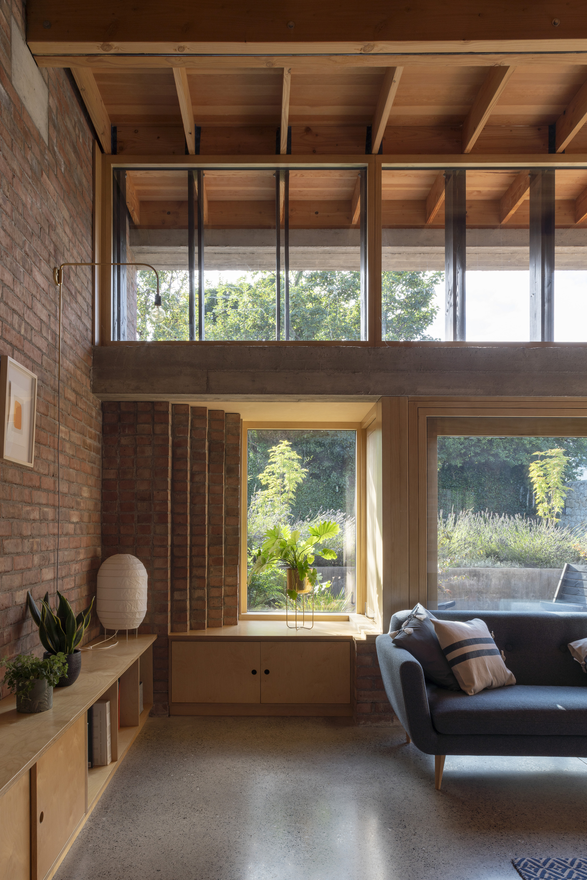 Built-in window seat framed by plywood panels with steel columns and timber joists overhead