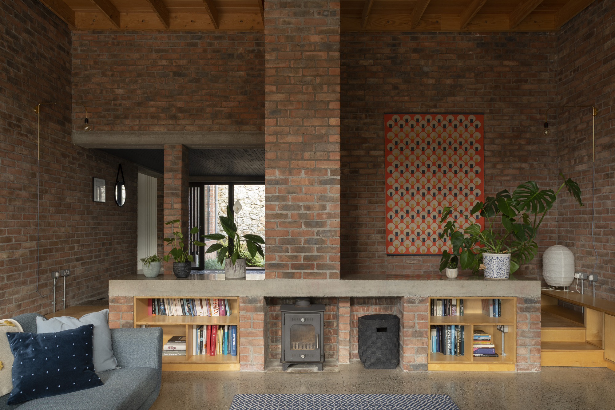 Brick fireplace with built-in bookshelves and exposed timber ceiling beams above a low seating area