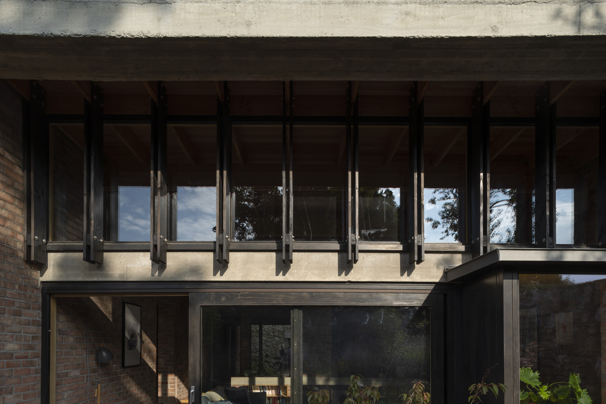 Cantilevered upper floor with exposed steel beams and concrete soffit overhanging glazed lower level