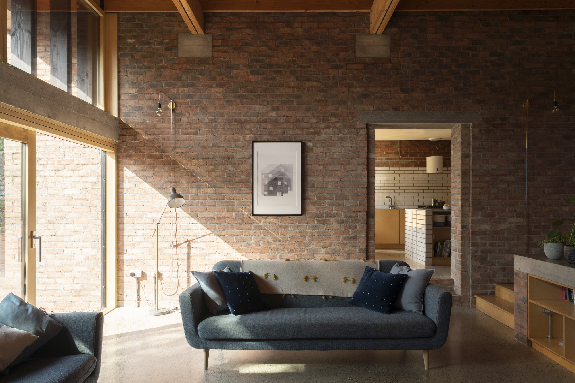 Living space with exposed brick wall and timber roof beams under diffused afternoon sunlight