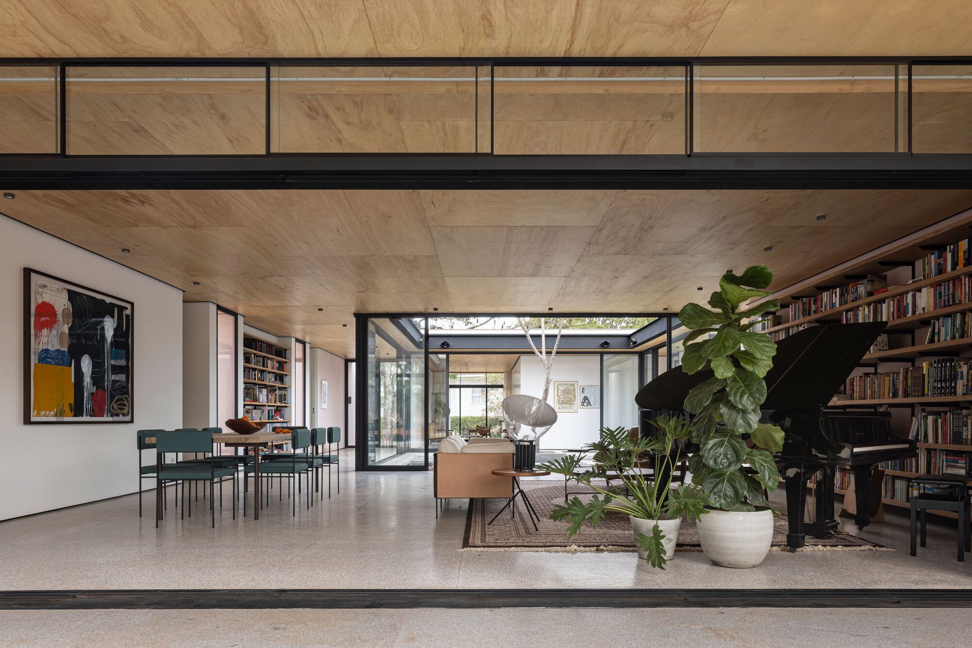 Open-plan living space with timber-clad ceiling and clerestory glazing overlooking the planted courtyard