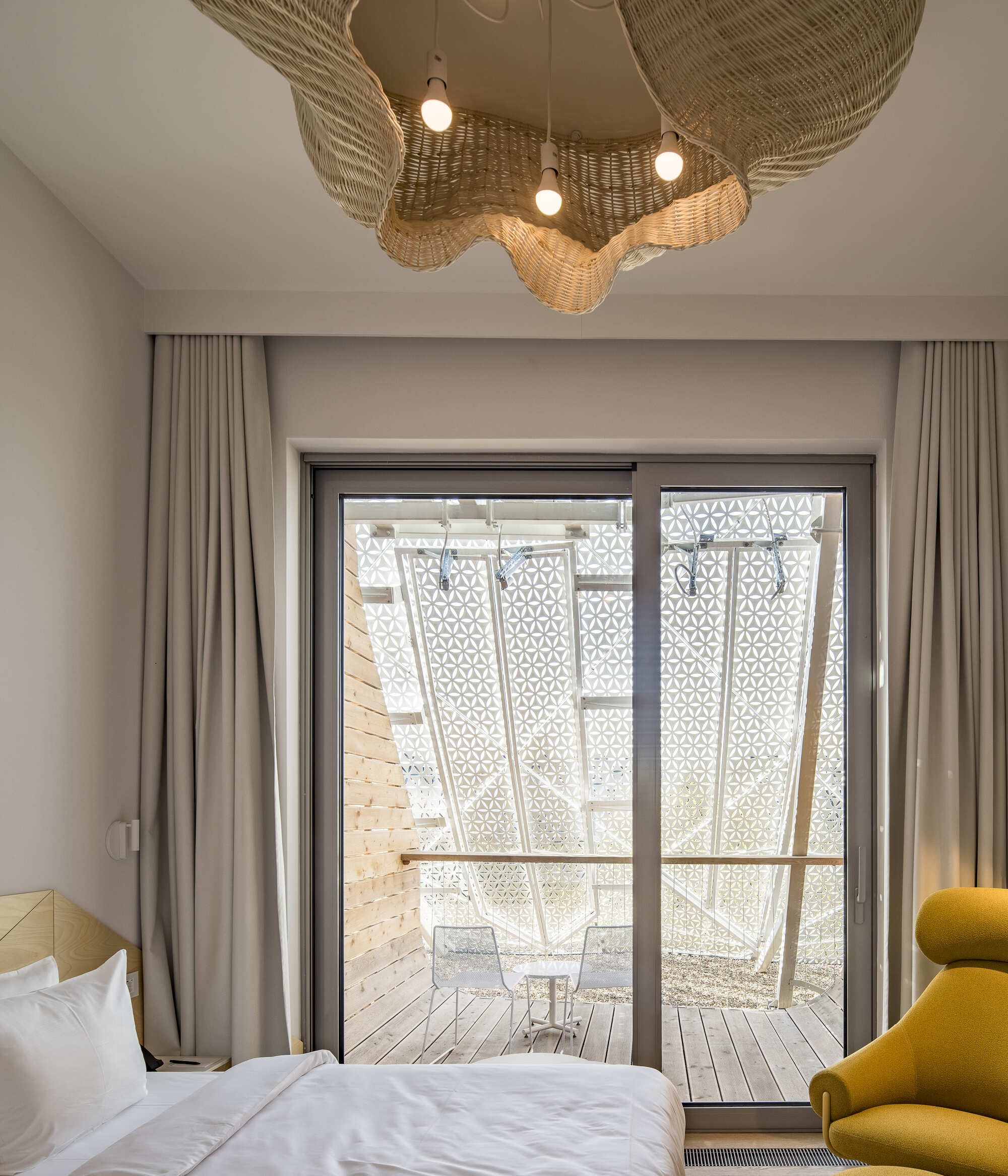 Glass doors framing a private terrace with patterned perforated screens and hammock in daylight