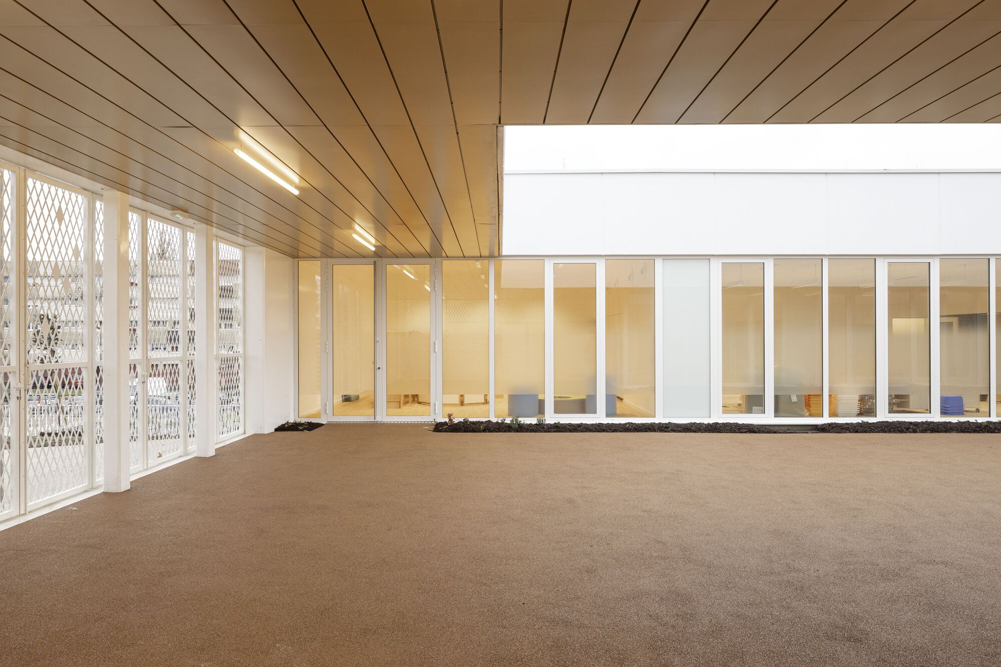Interior room with timber plank ceiling and perforated metal doors opening to a glazed corridor