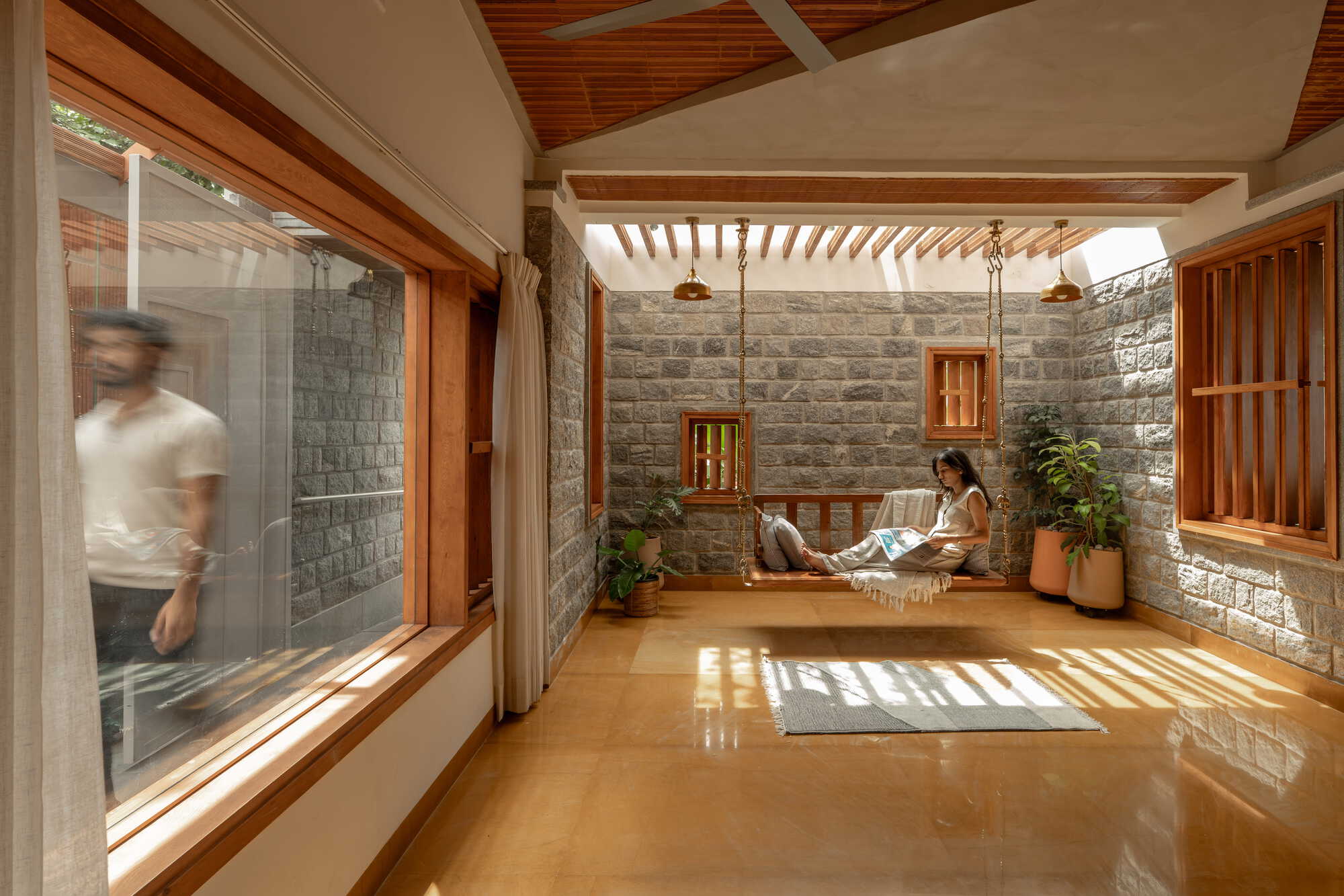 Interior courtyard with stone block walls, timber louvered ceiling and a person reading on the raised platform