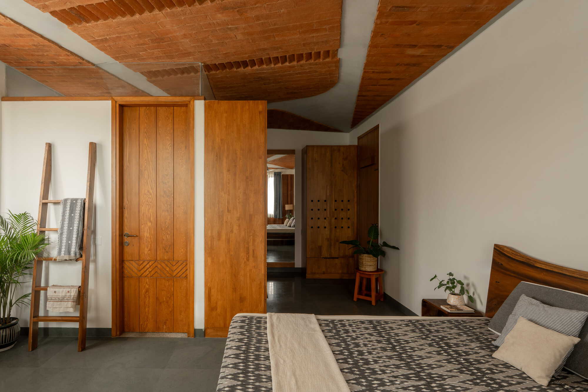 Bedroom with vaulted timber plank ceiling, built-in wooden wardrobes and view through to ensuite corridor