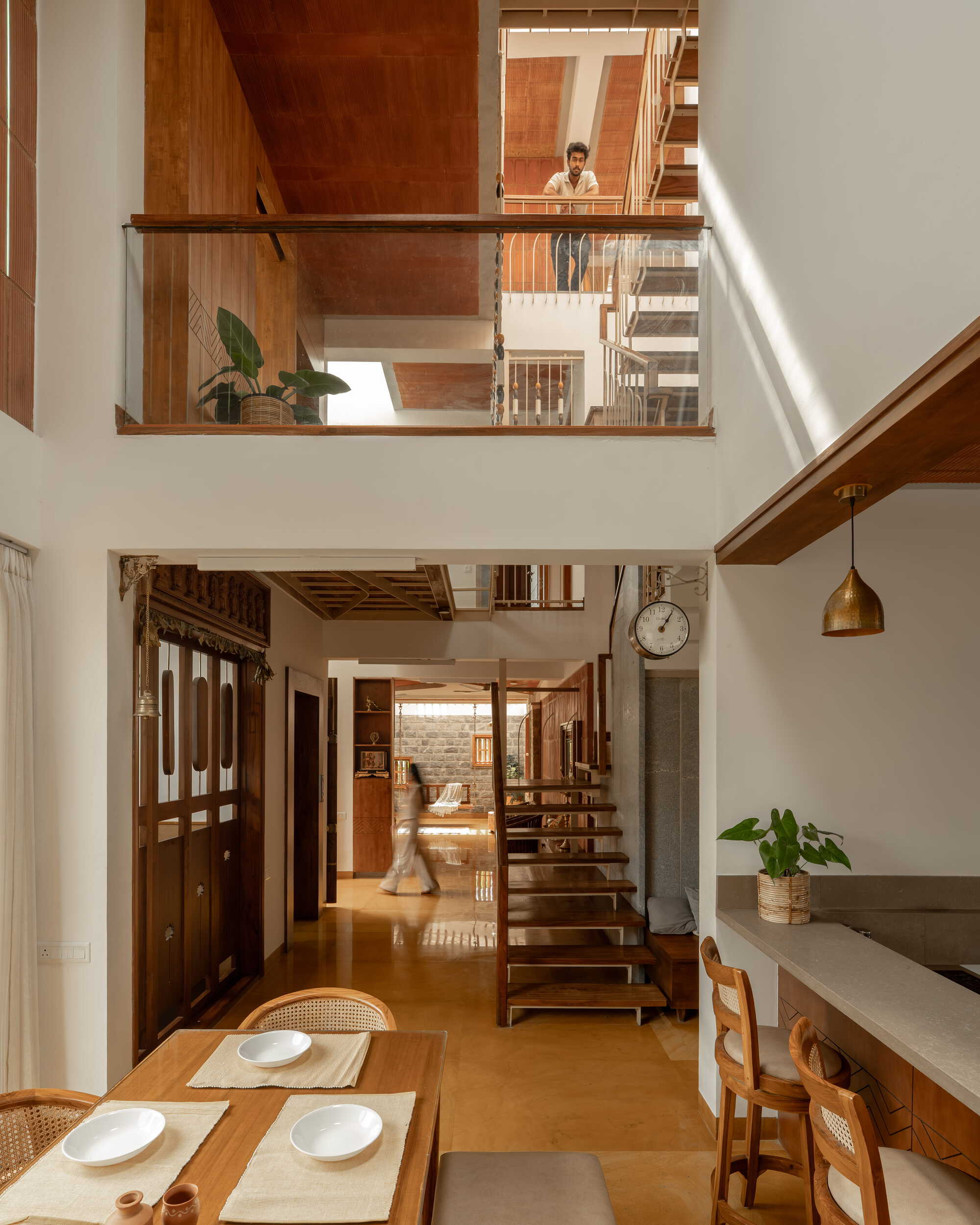 Double-height living and dining space with open timber staircases connecting three levels and a skylight above