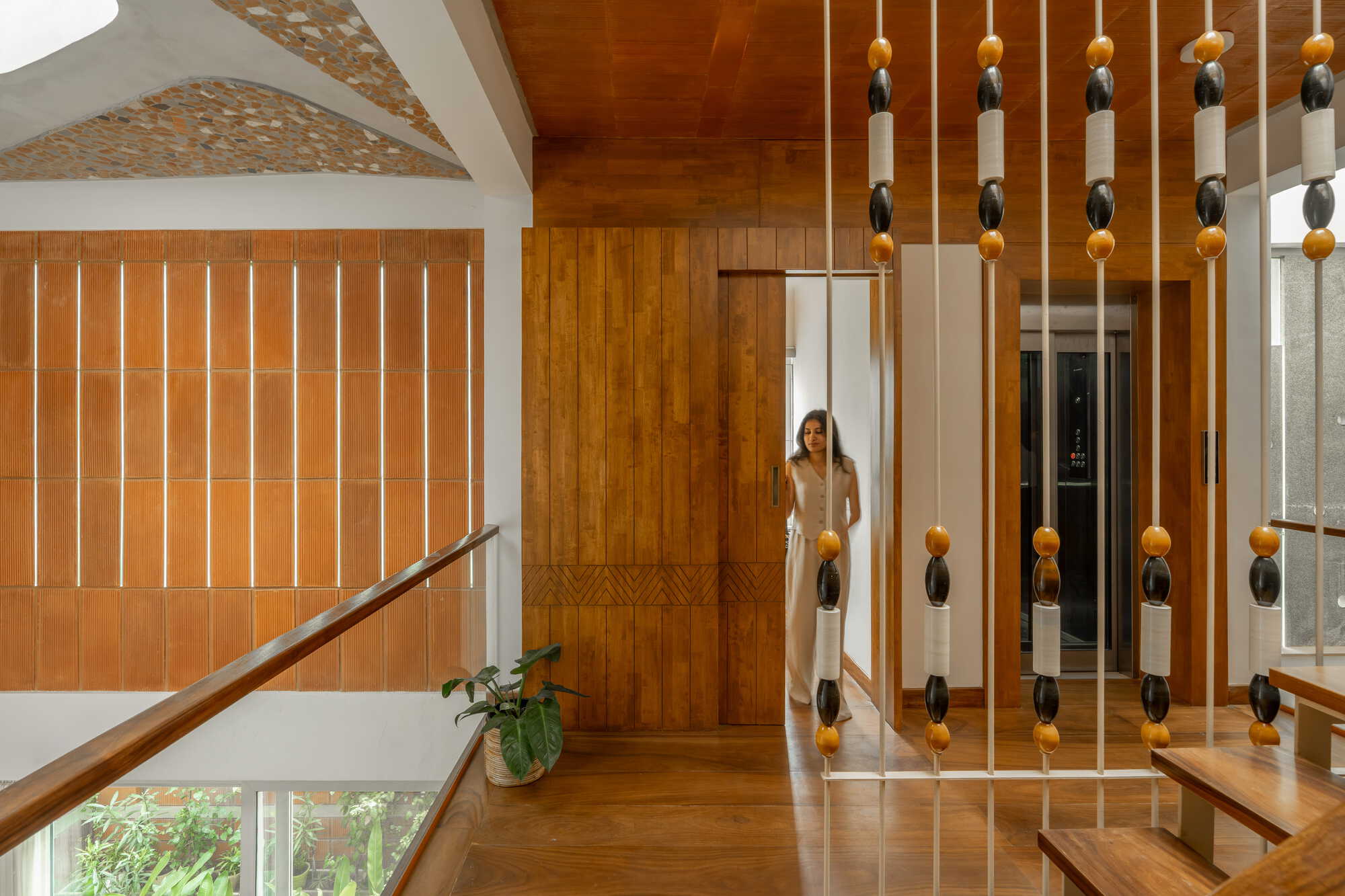 Upper landing with vertical timber screens and hanging bead divider as a person moves through the doorway