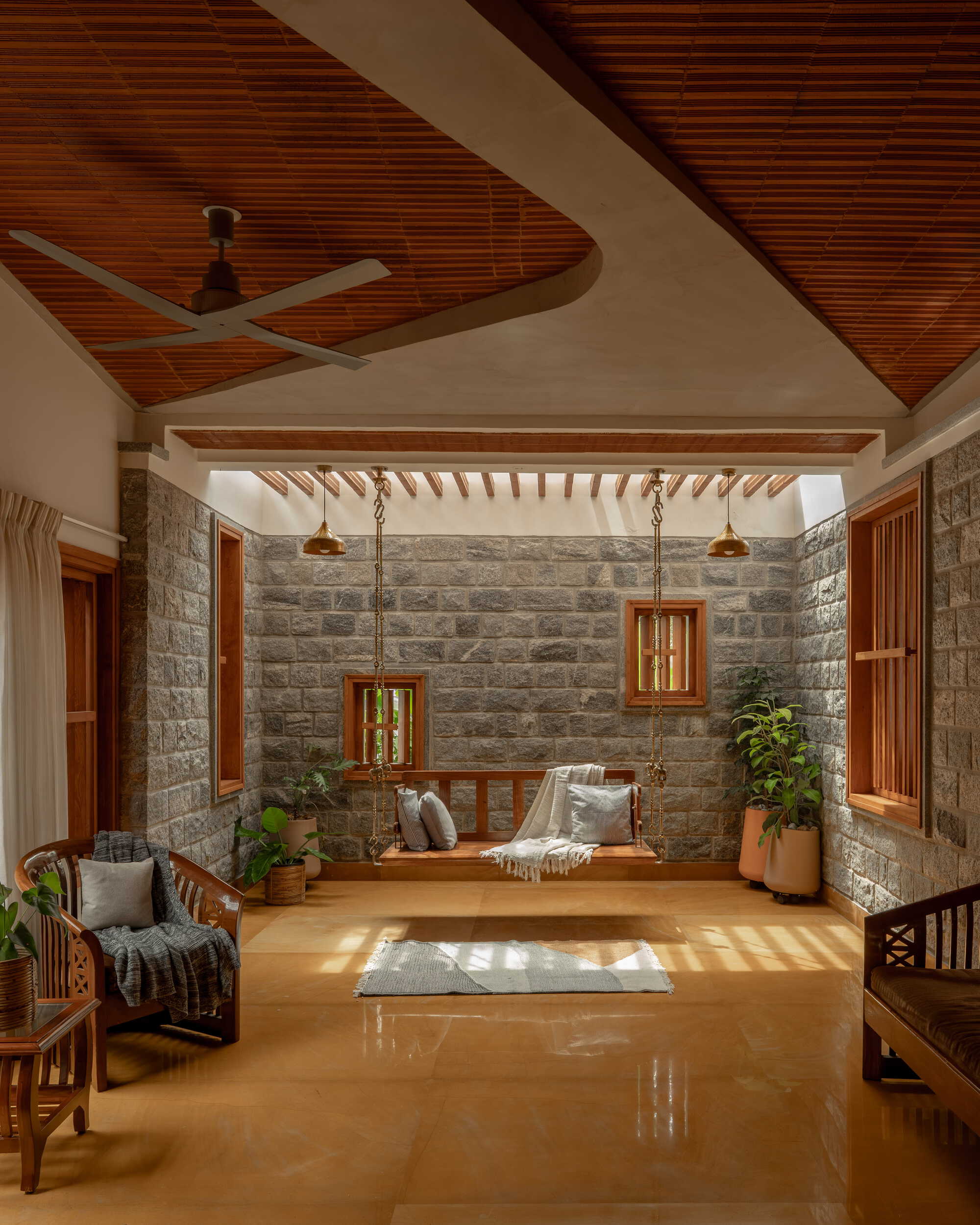 Semi-covered courtyard with stone walls, timber pergola and polished floor in dappled afternoon light