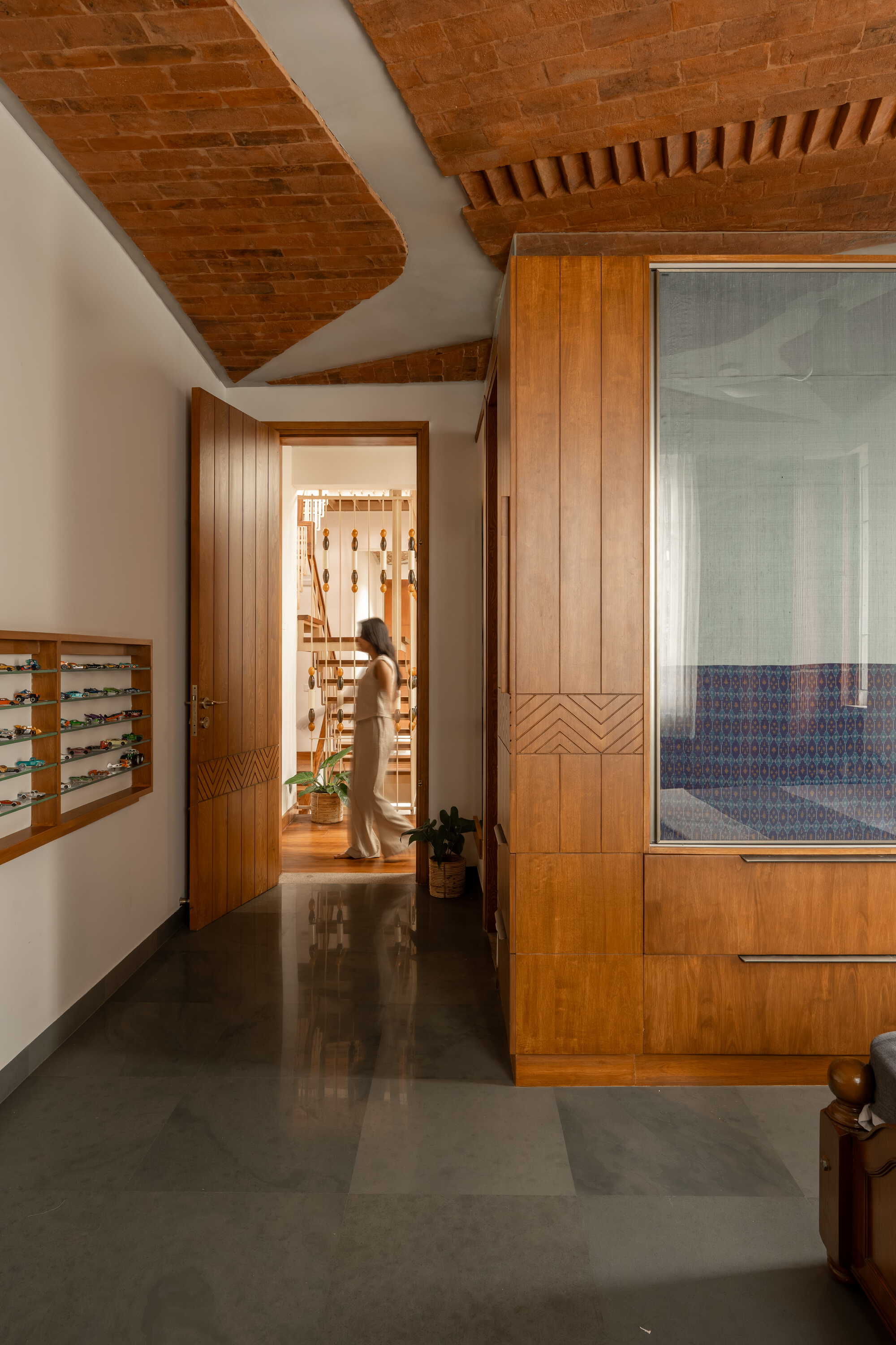 Corridor with vaulted brick ceiling and chevron-patterned timber door panels leading to interior rooms