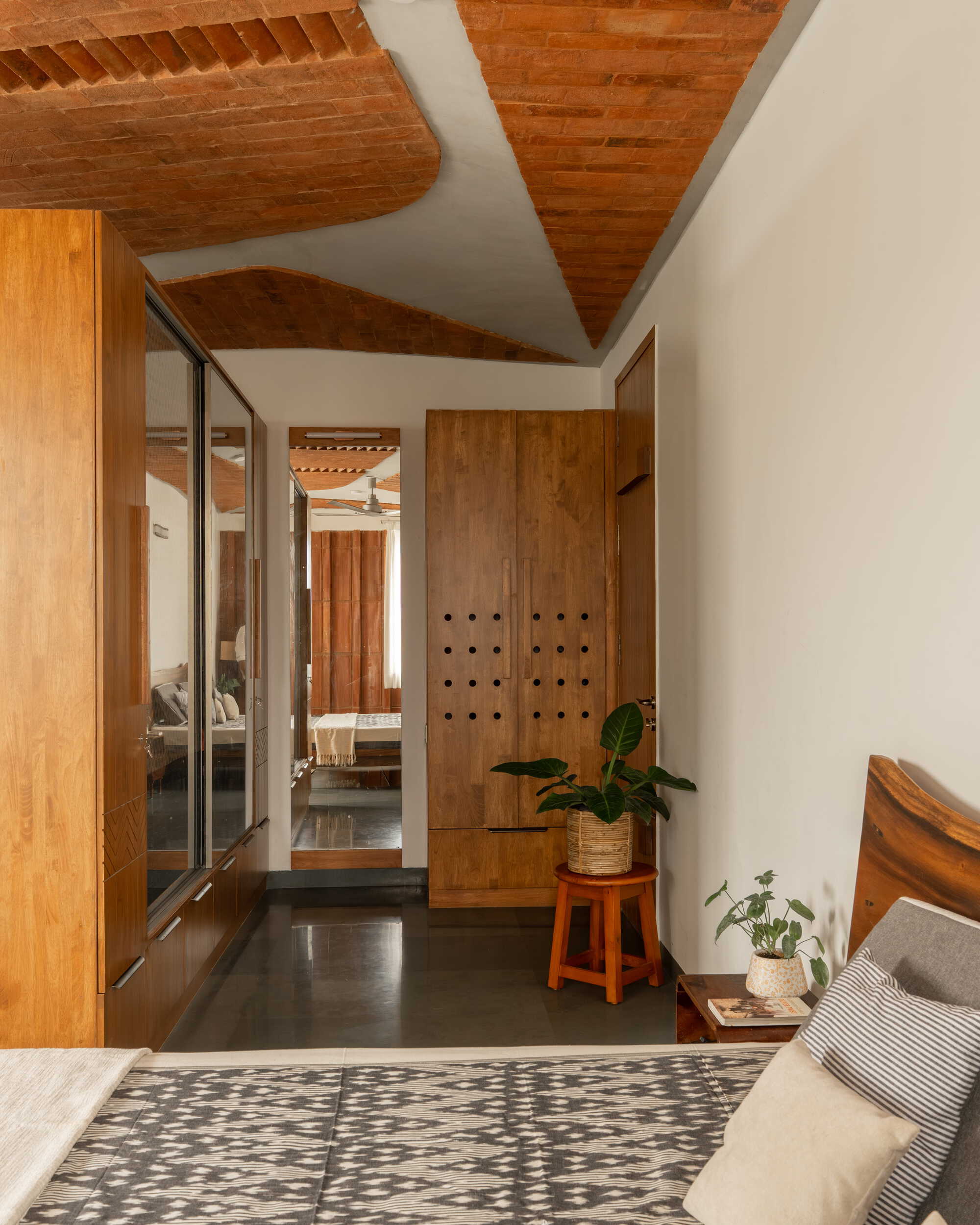 Bedroom view through to hallway showing vaulted brick ceiling and perforated timber wardrobe doors