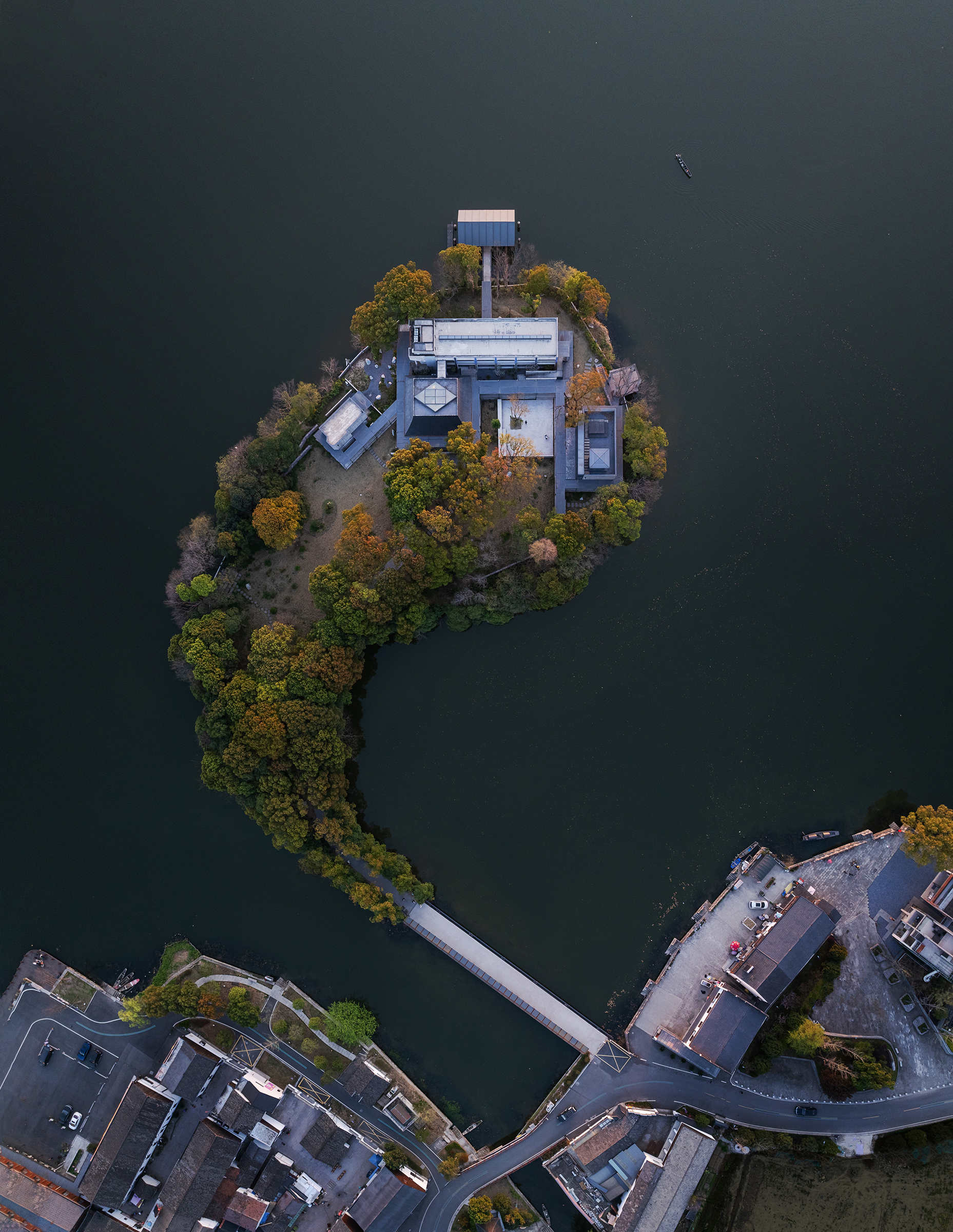 Aerial view of the pavilion on a small forested island connected by footbridge in autumn