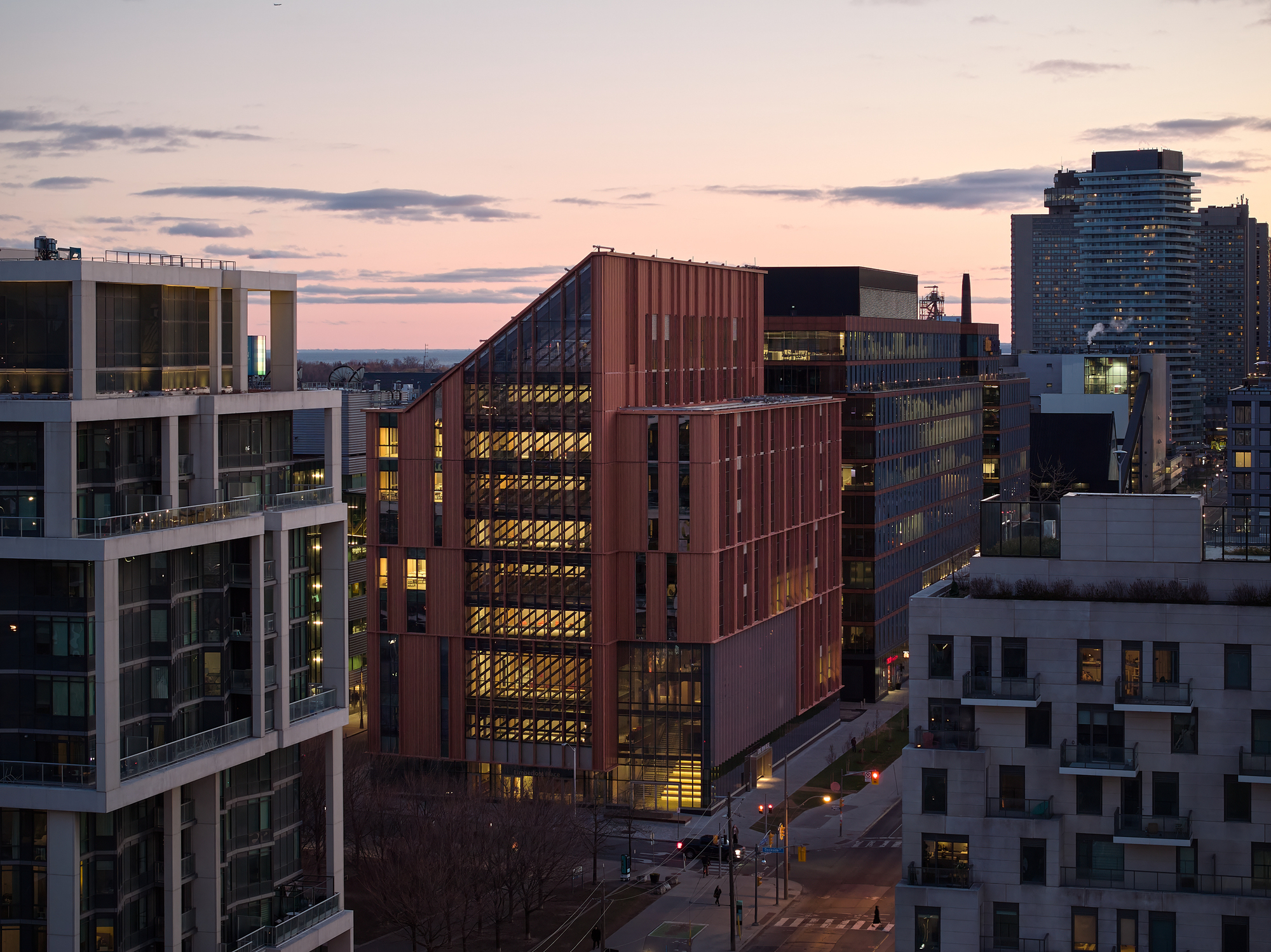 Corner view of the vertical copper cladding and recessed glazing lit from within at twilight