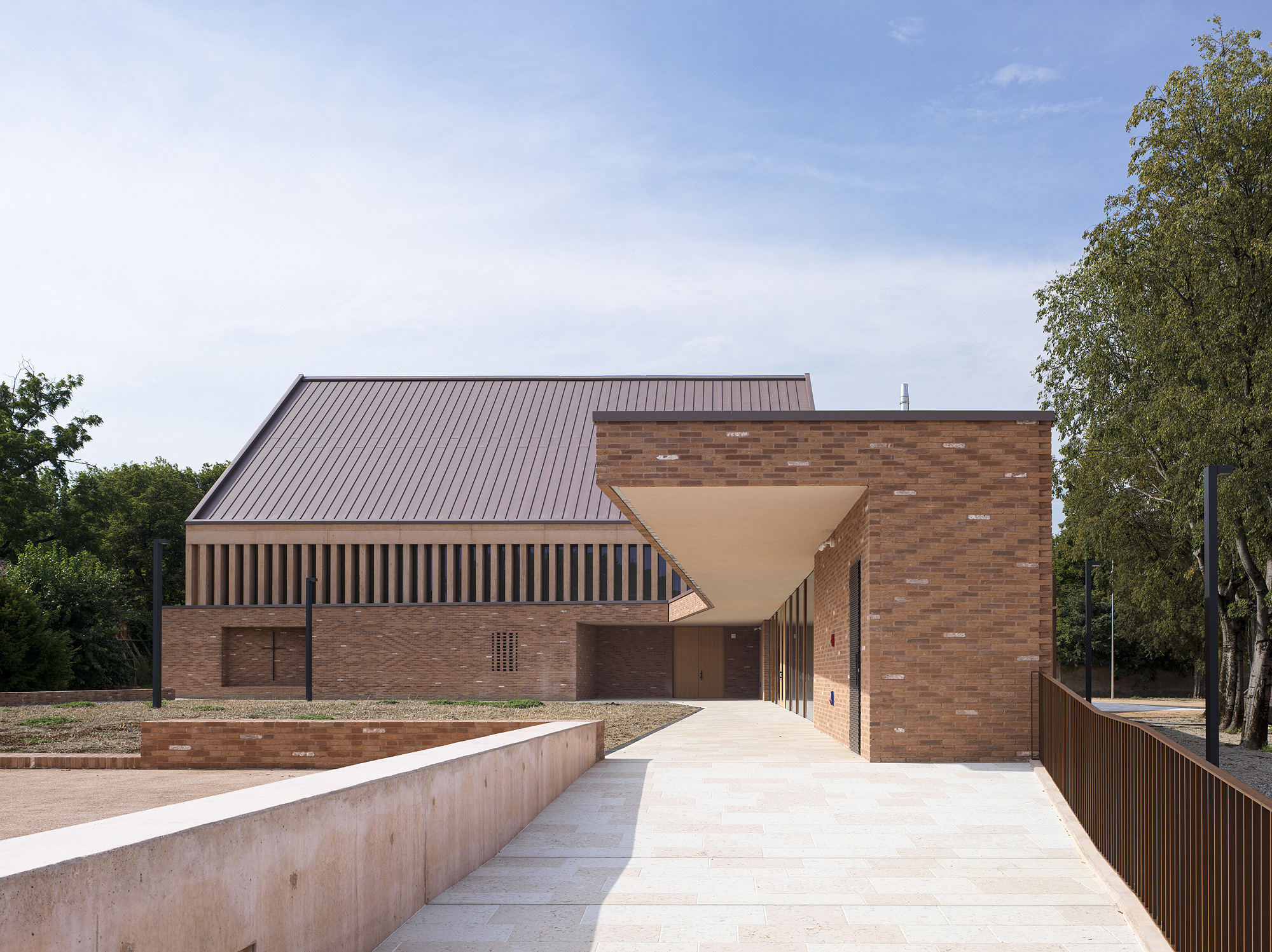 Entrance approach with a cantilevered canopy leading through brick walls and vertical timber screens