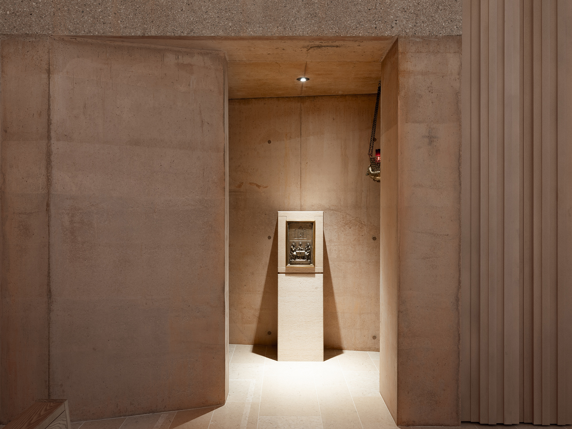 Narrow plywood-lined alcove with a white pedestal displaying a framed artifact under recessed lighting