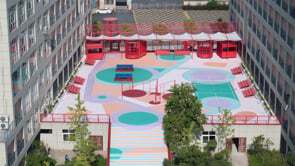 Aerial view of the rooftop courtyard with colorful geometric paving patterns and red pergola structures