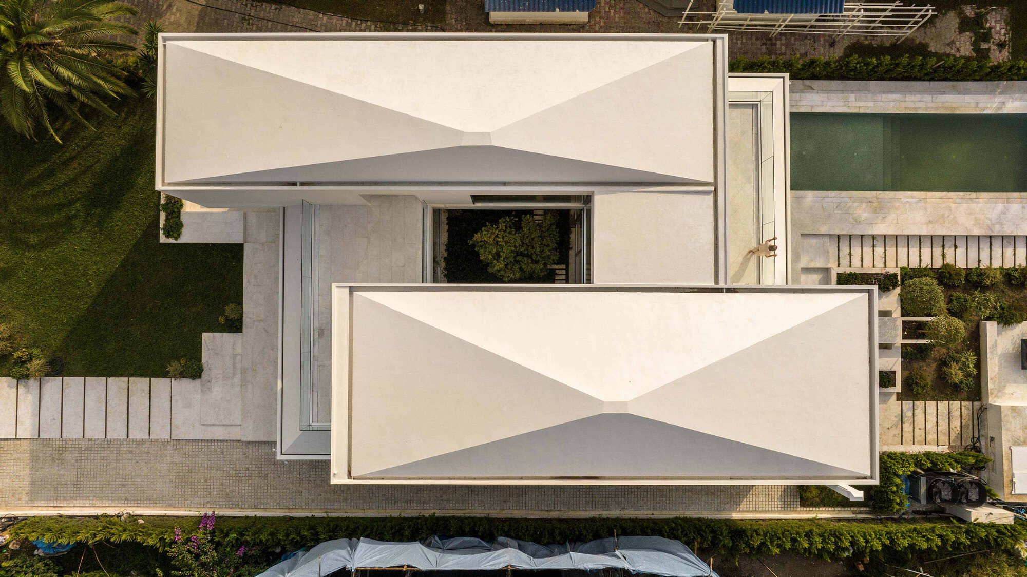 Aerial view of white cantilevered terraces with triangular shadow patterns and surrounding landscaping