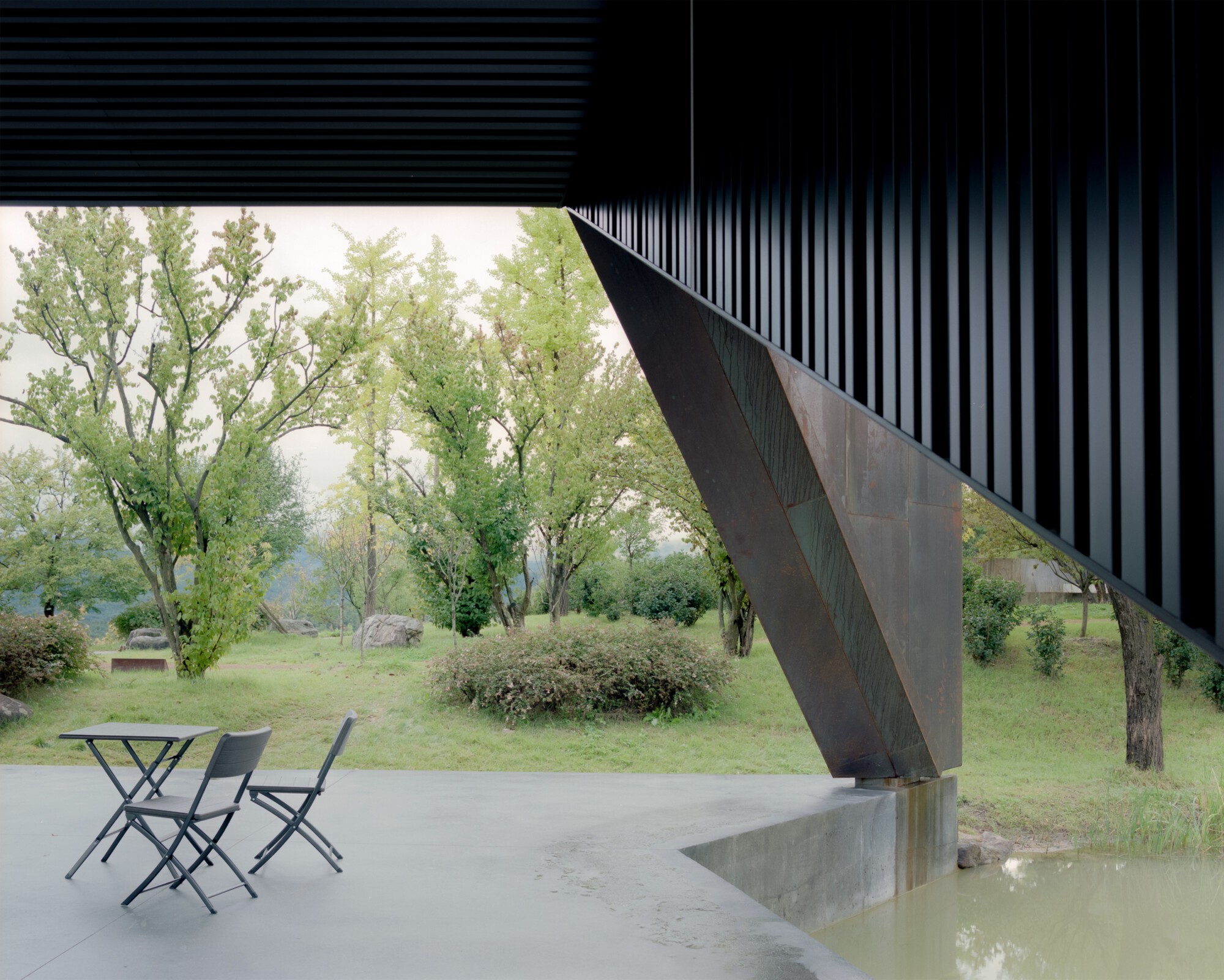 View from beneath the louvered soffit showing angular steel support and poolside seating area