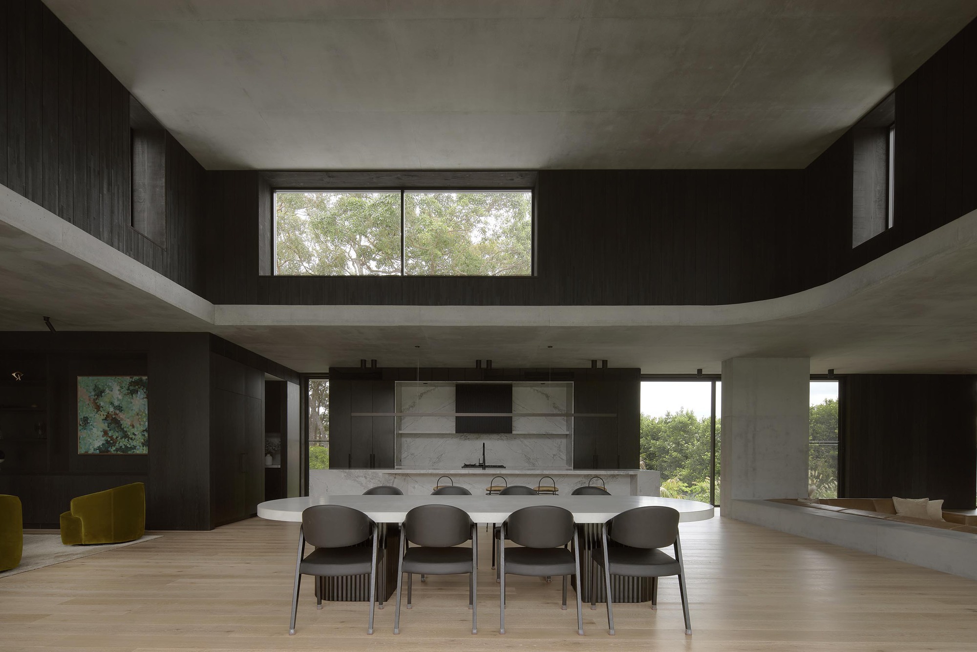Double-height dining space with concrete mezzanine, black timber walls and clerestory windows