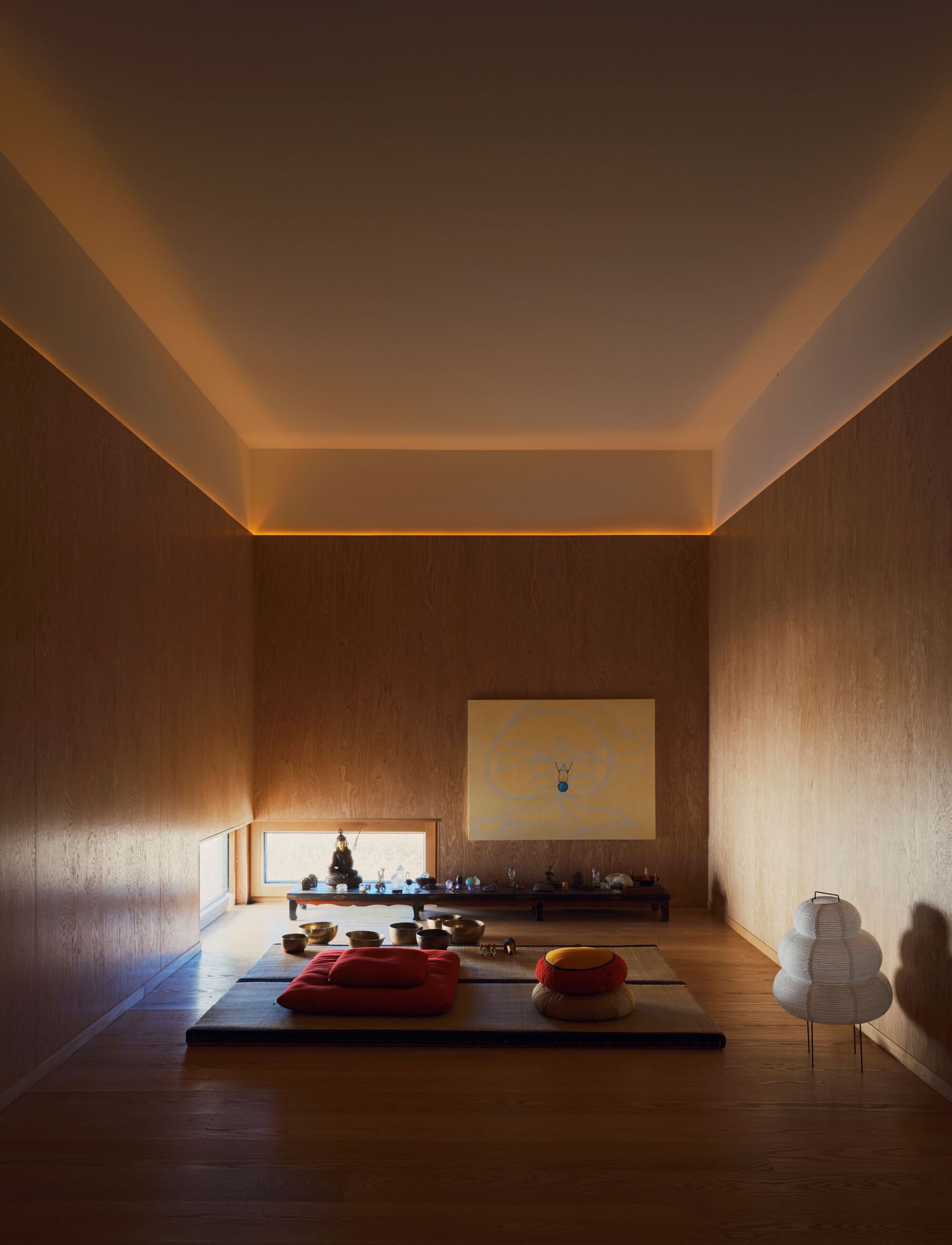 Meditation room with wood-paneled walls and indirect perimeter lighting washing the stepped ceiling