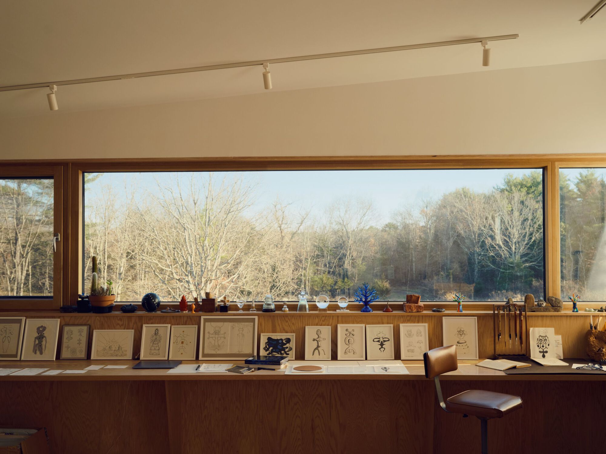 Continuous horizontal window with framed drawings displayed on the counter below in afternoon light