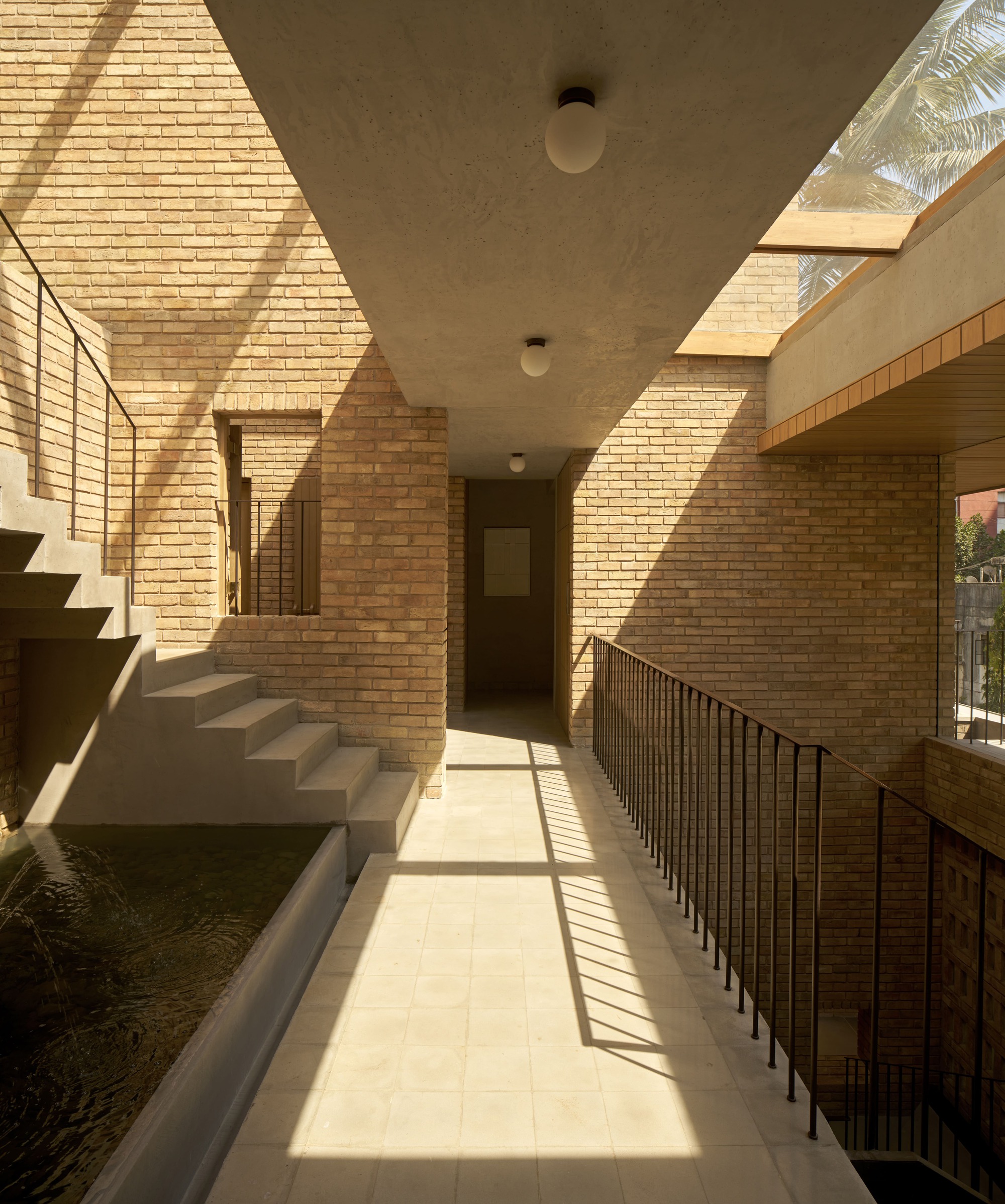 Upper corridor with perforated brick walls casting geometric shadows across the concrete ceiling
